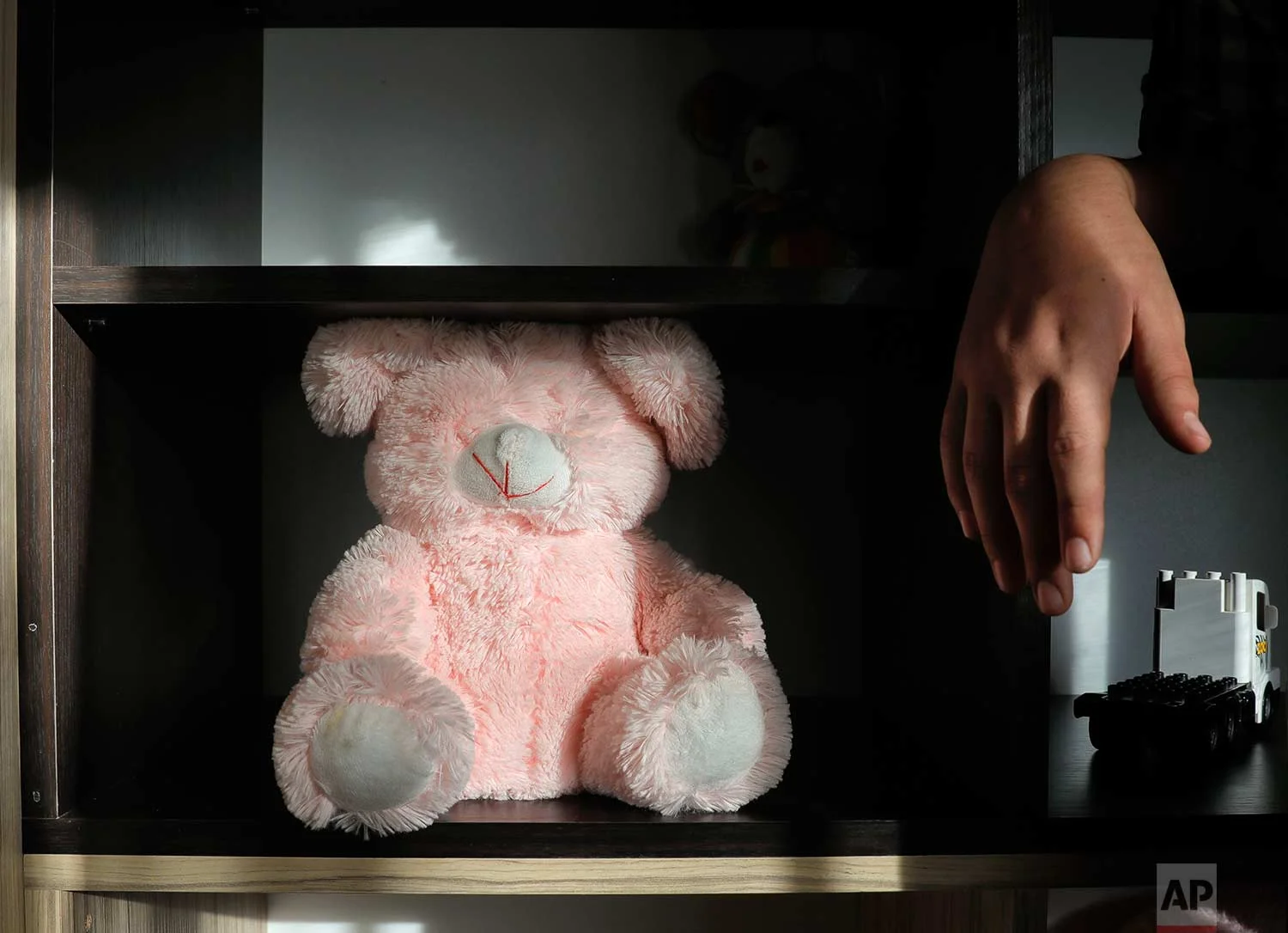 A boy stands next to a teddy bear missing its eyes at a foster home in Bucharest, Romania, on Wednesday, Nov. 1, 2017. (AP Photo/Vadim Ghirda)