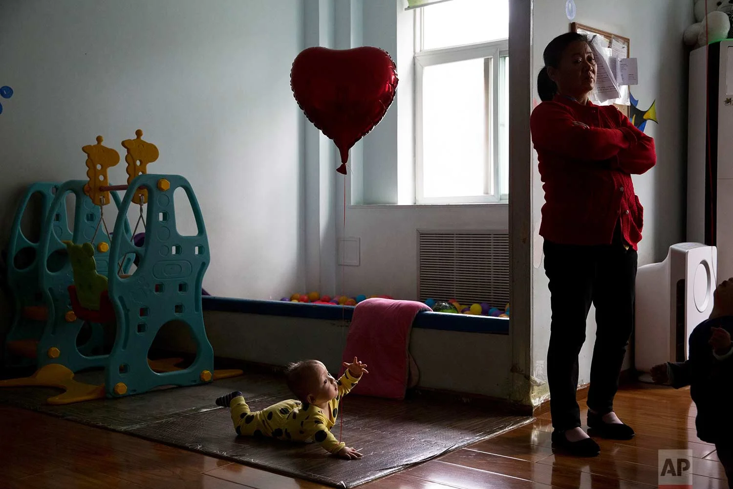 A child reaches towards a minder at a foster home of the New Hope Foundation, a charity that provides care and medical treatment for babies with deformities that can be corrected with surgery, on the outskirts of Beijing, China, on Wednesday, Oct. 11, 2017. (AP Photo/Ng Han Guan)