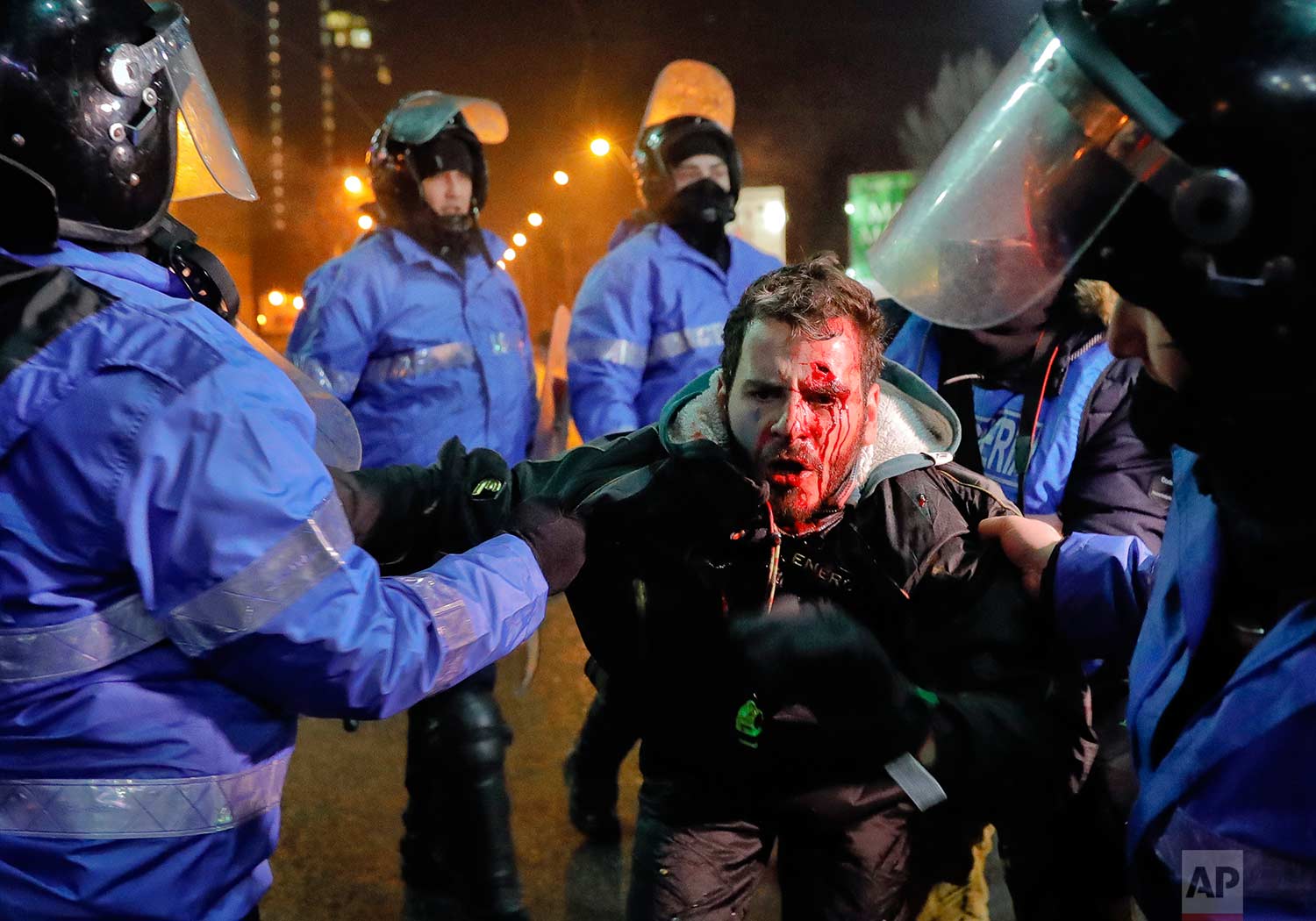  In this Thursday, Feb. 2, 2017 photo, Romanian riot police detain a man, face covered in blood, after minor clashes erupted during a protest in Bucharest, Romania. Brief clashes broke out between protesters and police in Romania's capital, as tens o