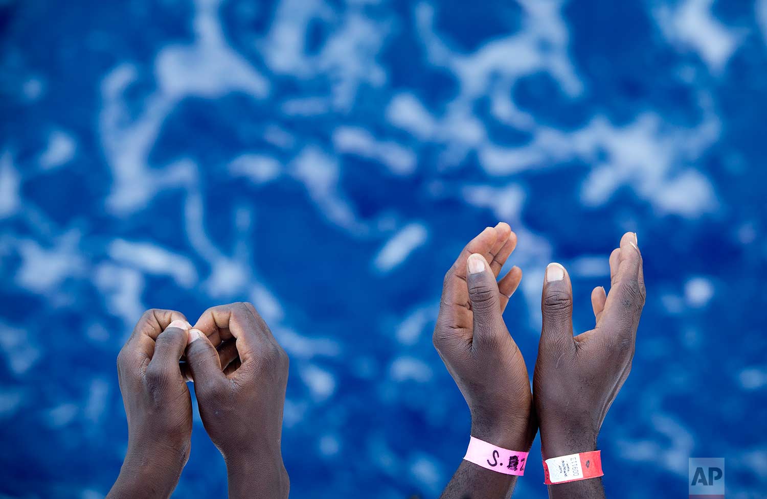  In this Thursday, Aug. 31, 2017 photo, African migrants gesture as stand on the deck of the Aquarius vessel of SOS Mediterranee and MSF (Doctors Without Borders) NGOs, in the Mediterranean Sea, southwest of Malta. 265 people rescued from the sea dur