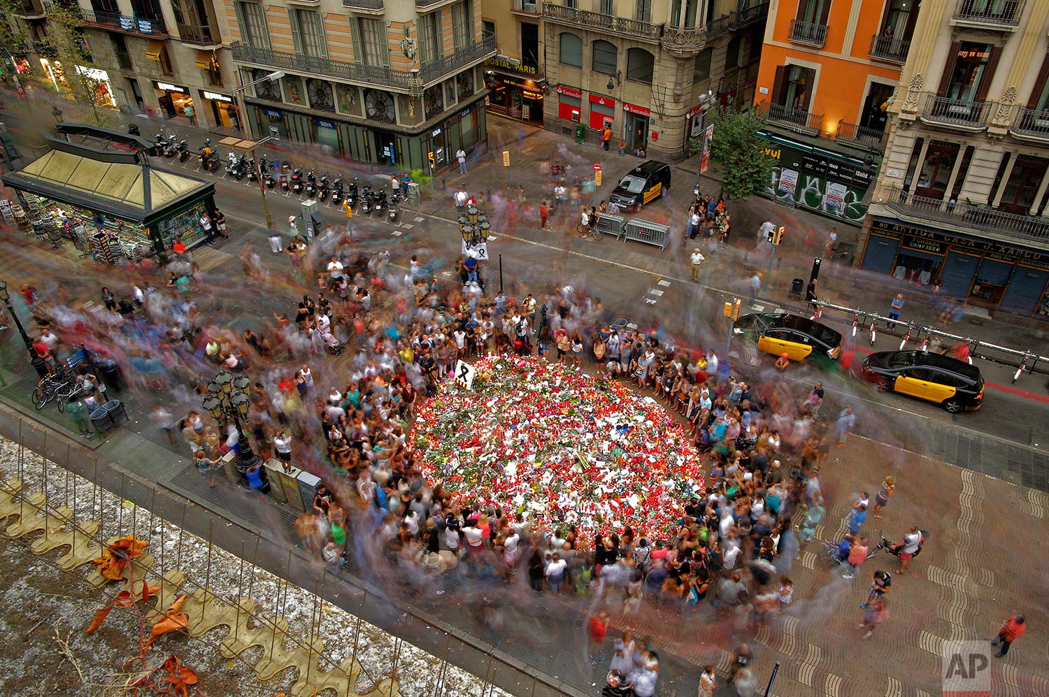  In this Saturday, Aug. 19, 2017 photo, people pay respect at a memorial tribute of flowers, messages and candles to the victims on Barcelona's historic Las Ramblas promenade on the Joan Miro mosaic, embedded in the pavement where the van stopped aft