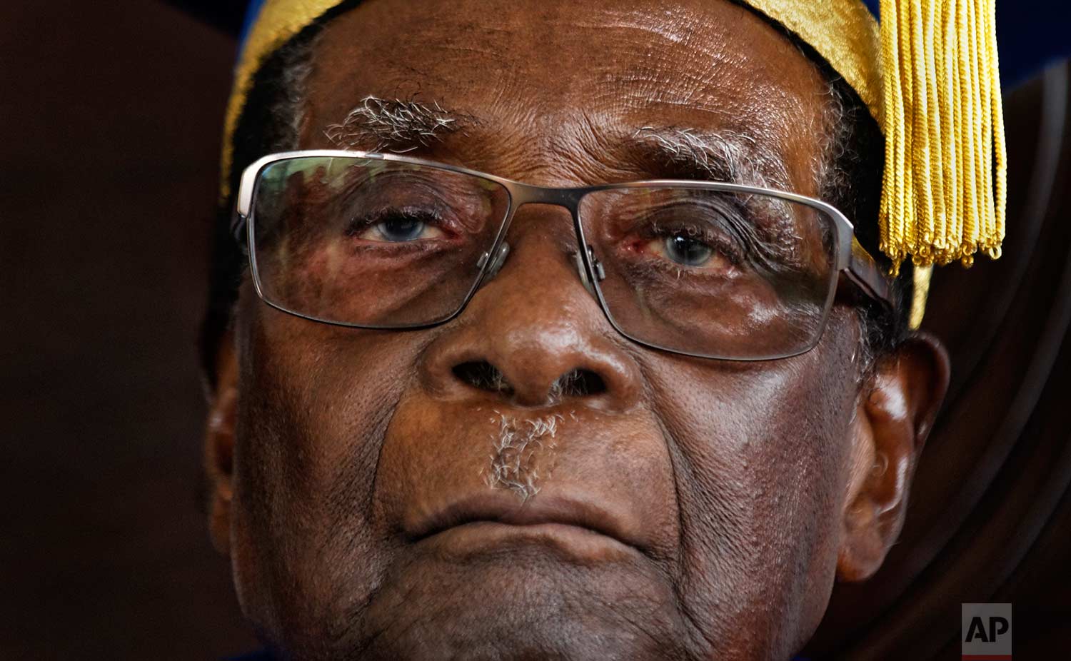  In this Friday, Nov. 17, 2017 photo, Zimbabwe's President Robert Mugabe sits for formal photographs with university officials, after presiding over a student graduation ceremony at Zimbabwe Open University on the outskirts of Harare, Zimbabwe. Mugab