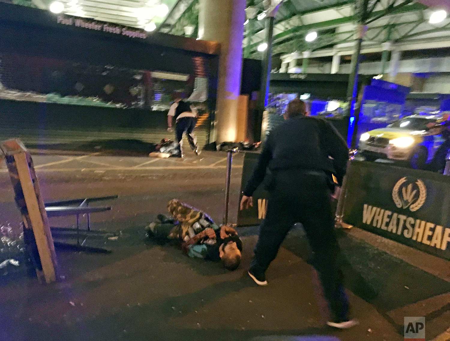  In this image provided by Gabriele Sciotto taken on Saturday, June 3, 2017, one of the suspects from the London Bridge attack, wearing what appear to be canisters strapped to his chest, lies on the ground after being shot by police outside Borough M