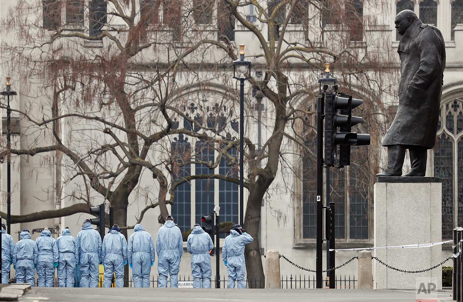  In this Thursday March 23, 2017 photo, police forensic officers work in Parliament Square overseen by the statue of Winston Churchill outside the Houses of Parliament in London. On Wednesday a knife-wielding man went on a deadly rampage, first drivi