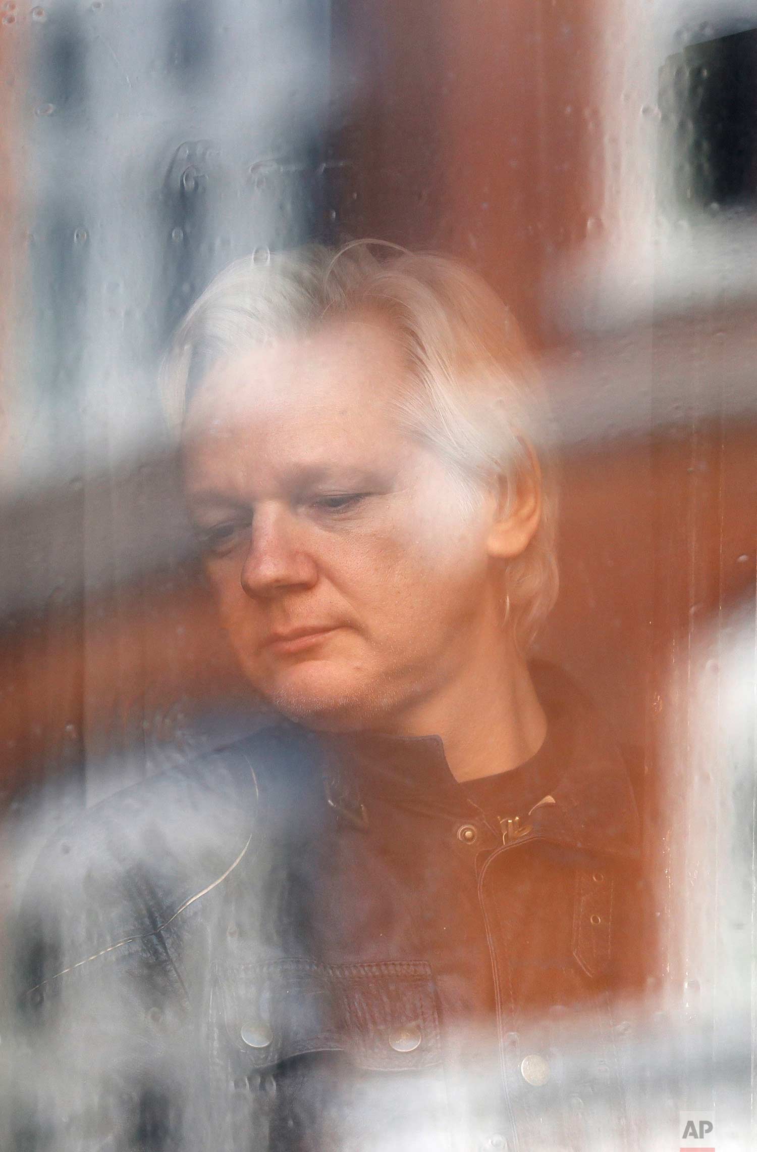  In this Friday May 19, 2017 photo, Julian Assange looks out the window from the Ecuadorian embassy in London. Sweden's top prosecutor says she is dropping an investigation into a rape claim against WikiLeaks founder Julian Assange after almost seven