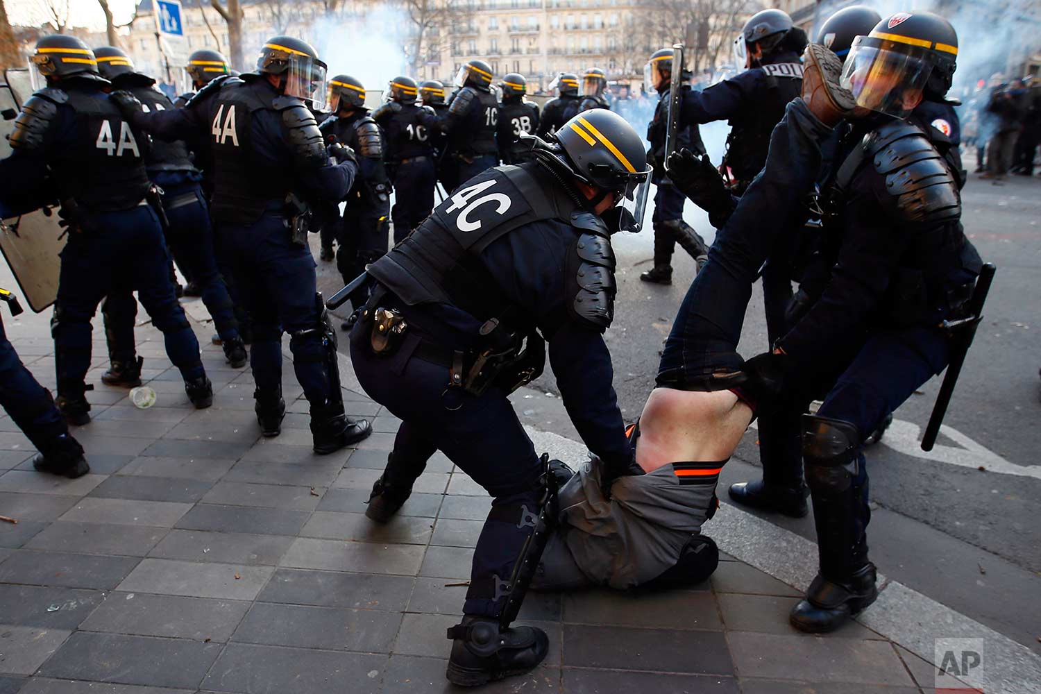  In this Saturday, Feb. 18, 2017 photo, riot Police officers apprehend a protester during clashes at a demonstration against alleged police abuse, in Paris. Anti-racism groups and other activists are gathered in Paris in support of victims of police 