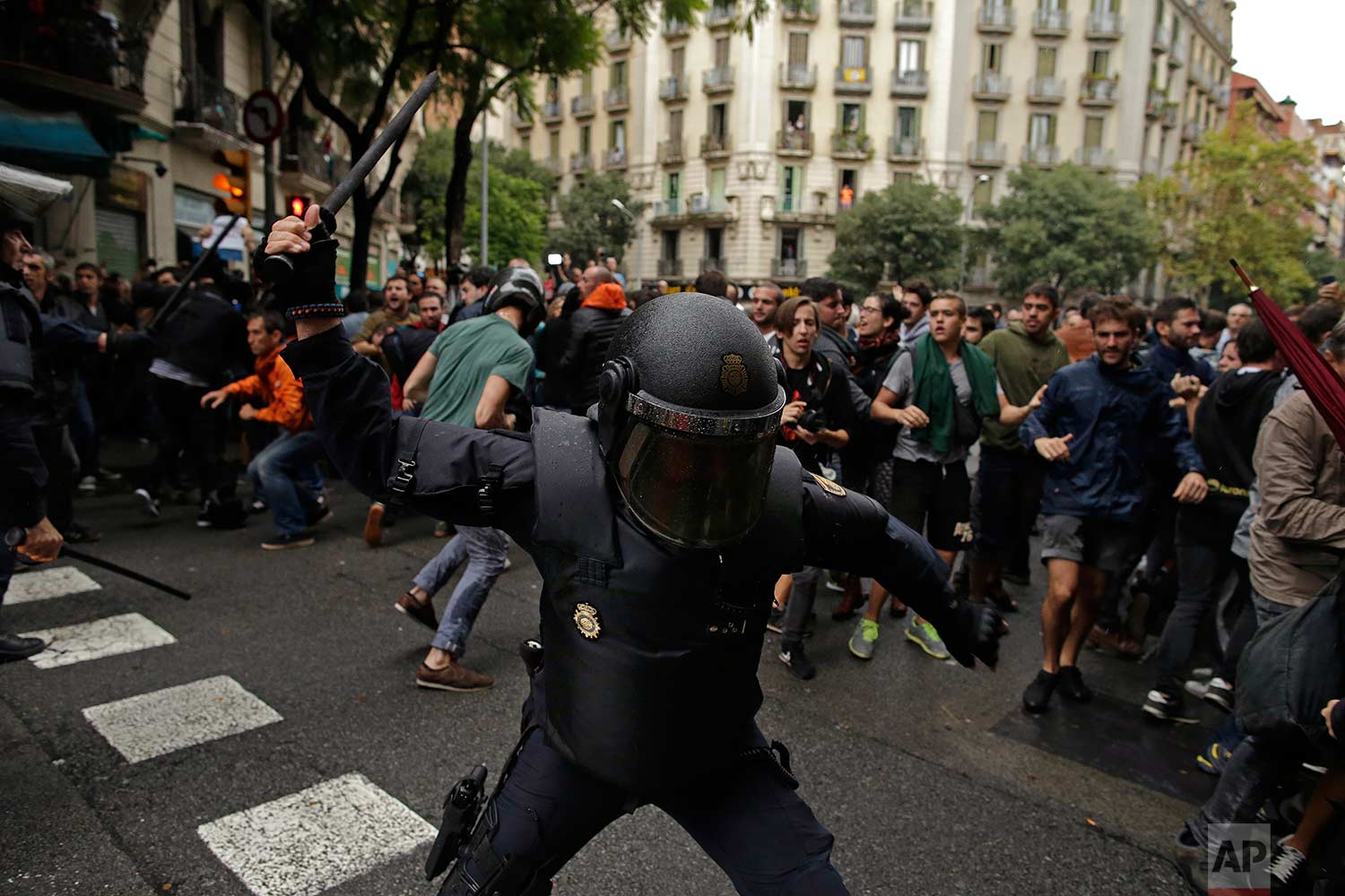  In this Sunday, 1 Oct. 2017 photo, Spanish riot police swings a club against would-be voters near a school assigned to be a polling station by the Catalan government in Barcelona, Spain. Spanish riot police have forcefully removed a few hundred woul