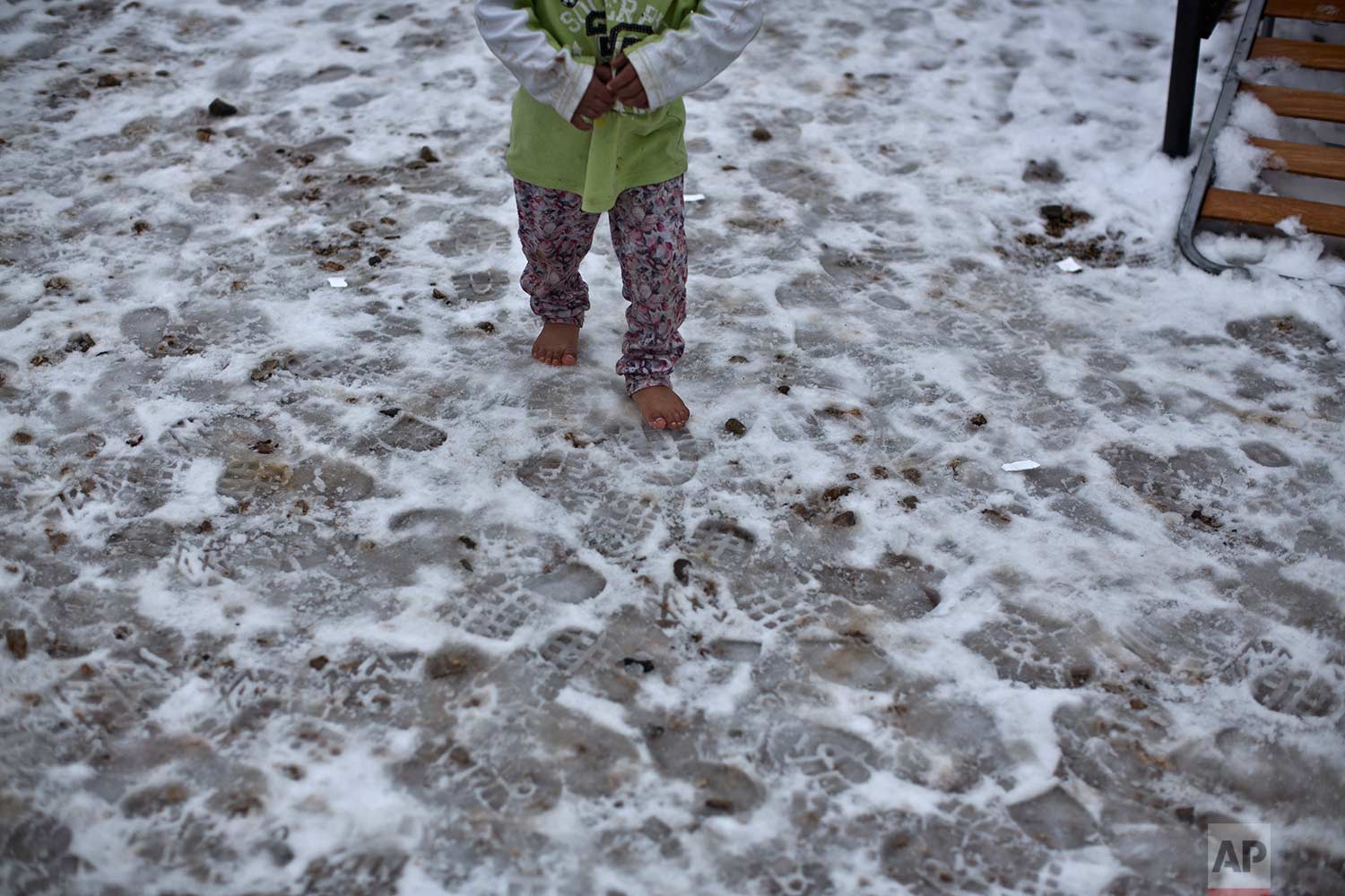  In this Wednesday, Jan. 11, 2017 photo, a Syrian refugee child walks barefoot on frozen ground at the refugee camp of Ritsona about 86 kilometers (53 miles) north of Athens. The European Commission said conditions for refugees on islands and other c