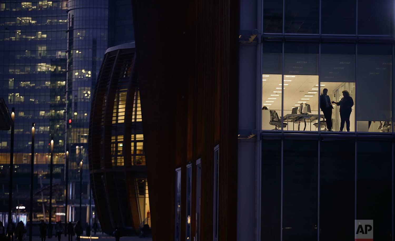  In this Wednesday, Oct. 18, 2017 photo, people are silhouetted behind the windows of an office, in Milan's Porta Nuova business district, Italy. (AP Photo/Luca Bruno) 
