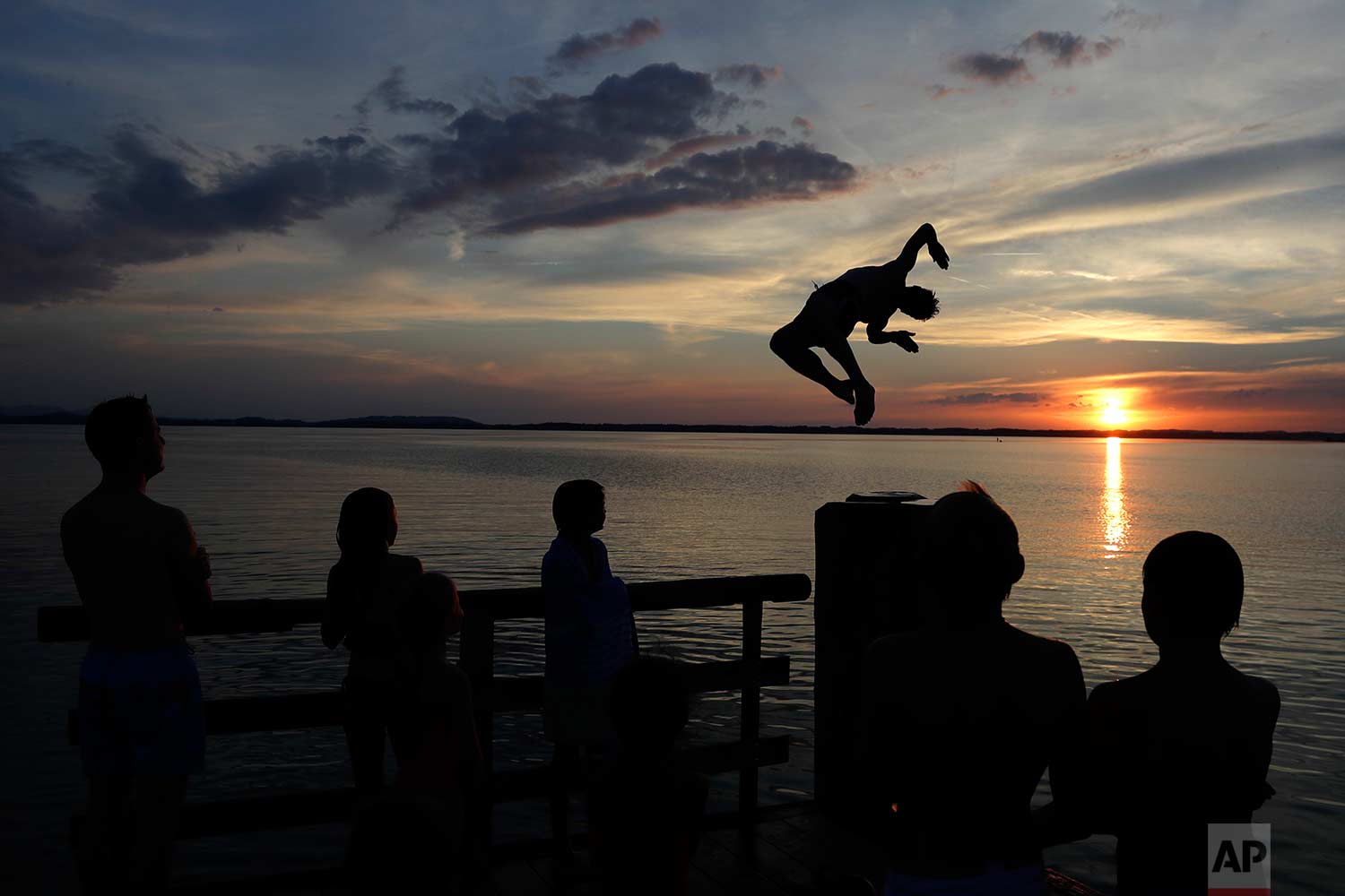  In this Saturday, July 22, 2017 photo, a man jumps into the water surrounded by his family at lake 'Chiemsee' in Chieming, Germany. (AP Photo/Matthias Schrader) 