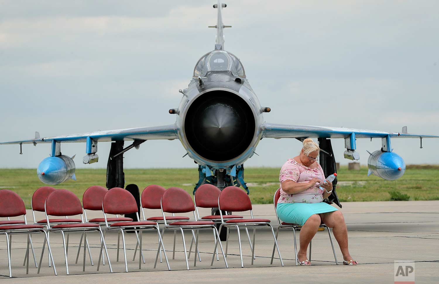  In this Wednesday, June 14, 2017 photo, a journalist, backdropped by a Soviet era built MIG 21 Romanian Air Force jet fighter operates a phone while waiting for Britain's defense minister Michael Fallon's arrival at the Mihail Kogalniceanu air base,