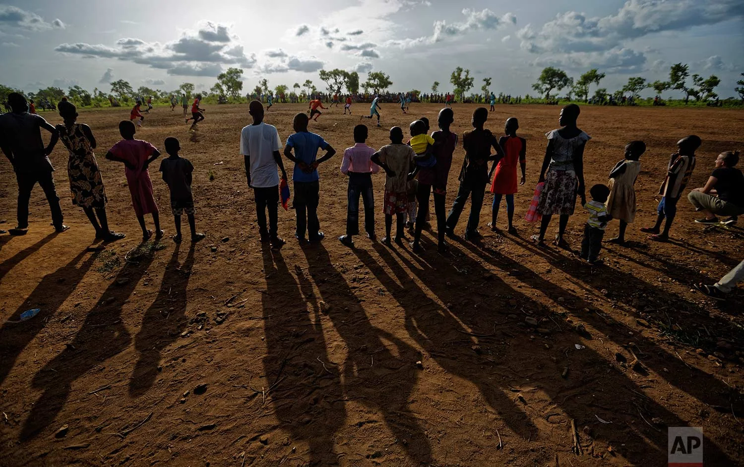 In this photo taken Sunday, June 4, 2017, South Sudanese refugees watch a match between refugee men's soccer teams, in the Bidi Bidi refugee settlement in northern Uganda. Soccer fields and inter-village competitions are found across the world's lar