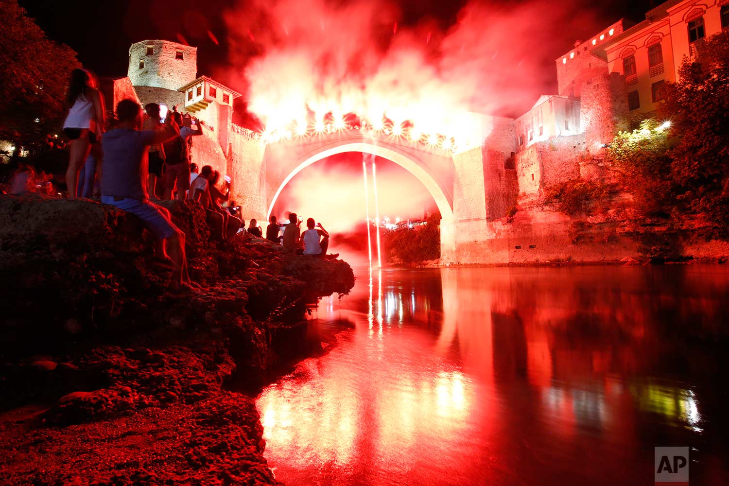  In this Sunday, July 30, 2017 photo, a Bosnian jumper, launches himself while holding burning torches, during traditional night jump from the Old Mostar Bridge, in Mostar, 140 kms south of Bosnian capital of Sarajevo. A total of 41 divers from Bosni