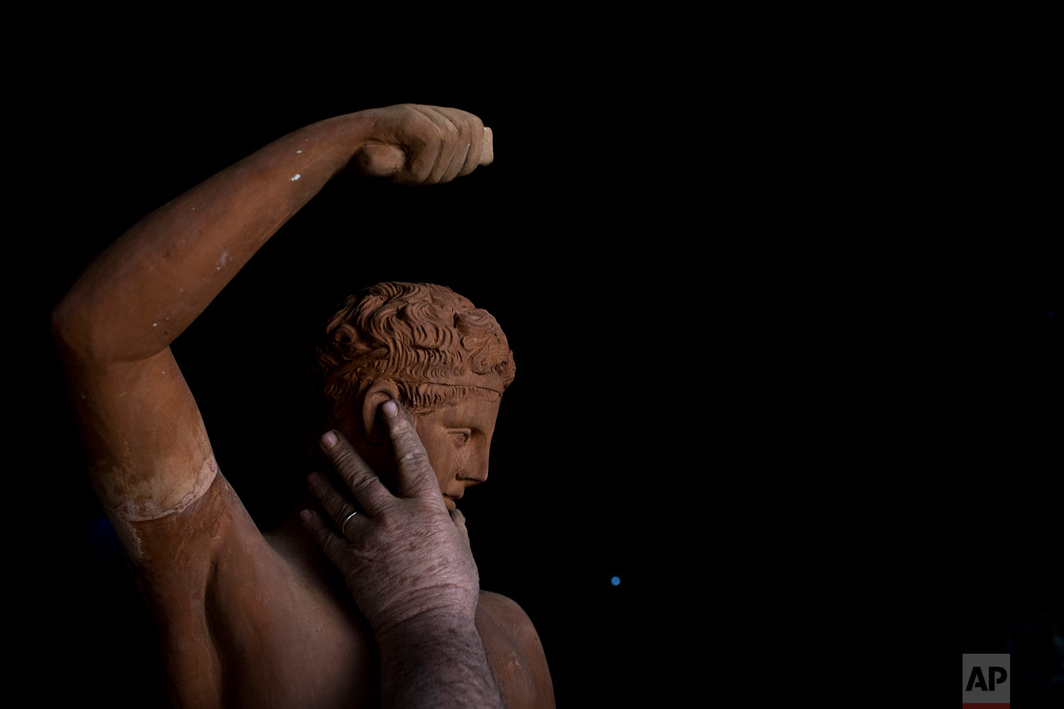  In this Tuesday, Dec. 19, 2017 photo, sculptor and ceramicist Haralambos Goumas touches a terracotta statue of Hermes, messenger of the ancient Greek gods, at his workshop in the Egaleo suburb of Athens. (AP Photo/Petros Giannakouris) 