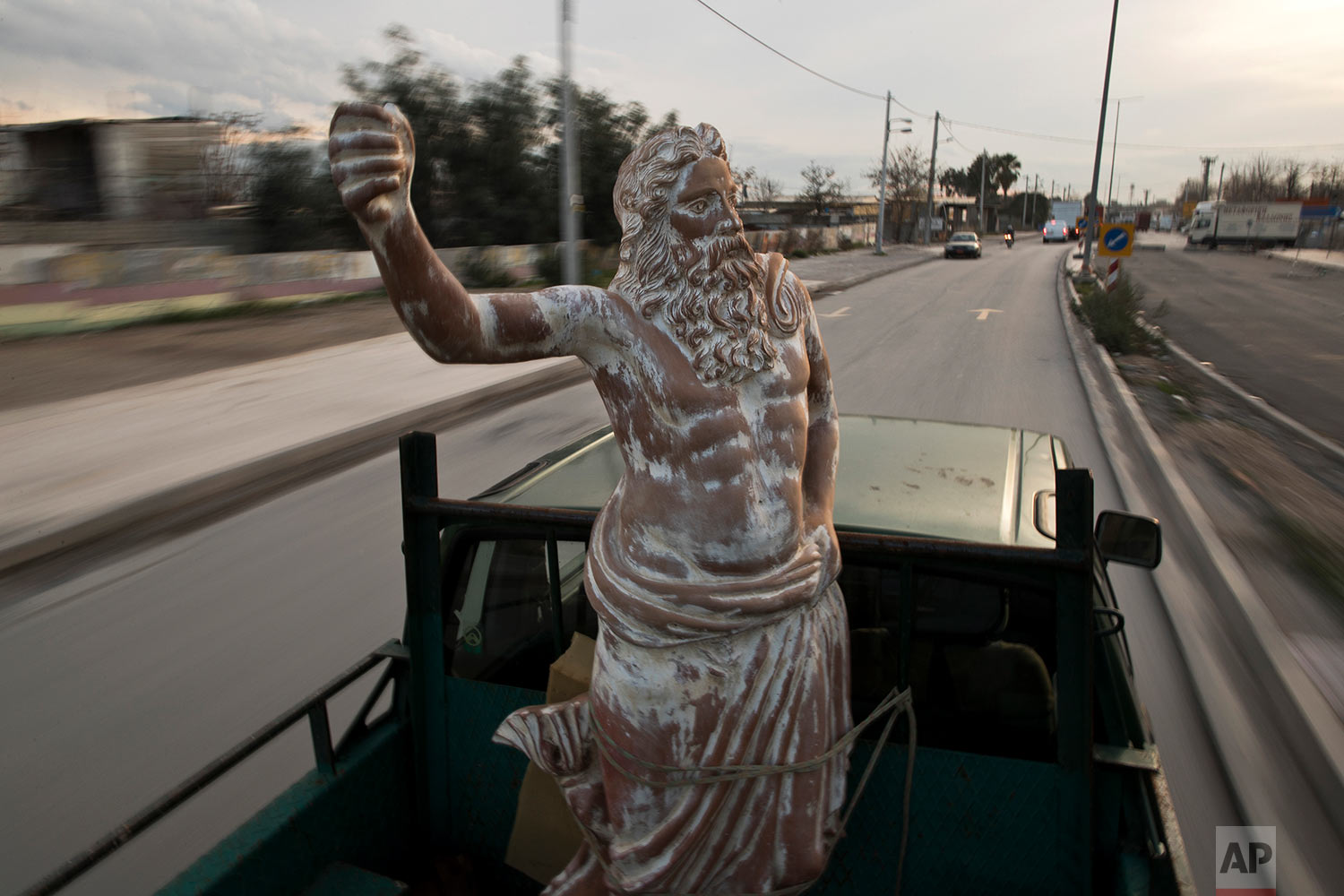  In this Tuesday, Dec 19, 2017 photo, a pickup track drives on a street of Athens carrying a terracotta statue of Zeus, chief among the ancient Greek gods, made by sculptor and ceramicist Haralambos Goumas. (AP Photo/Petros Giannakouris) 