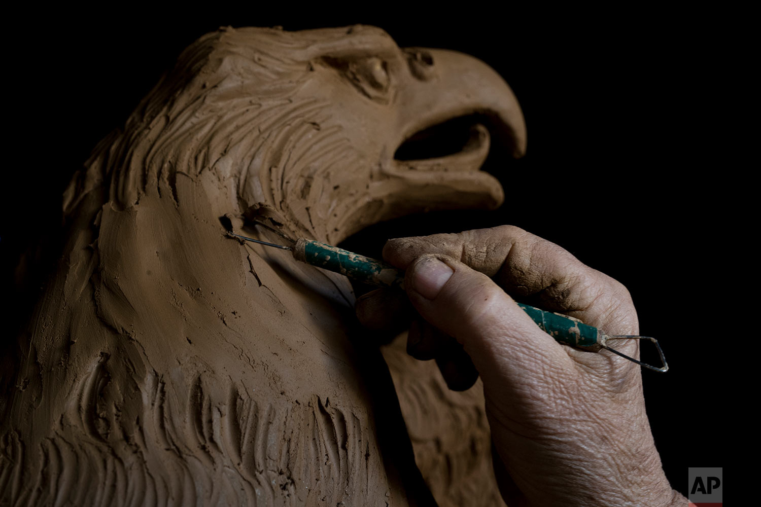  In this Tuesday, Nov. 14, 2017 photo, sculptor and ceramicist Haralambos Goumas works on a terracotta eagle, at his workshop, in the Egaleo suburb of Athens. (AP Photo/Petros Giannakouris) 