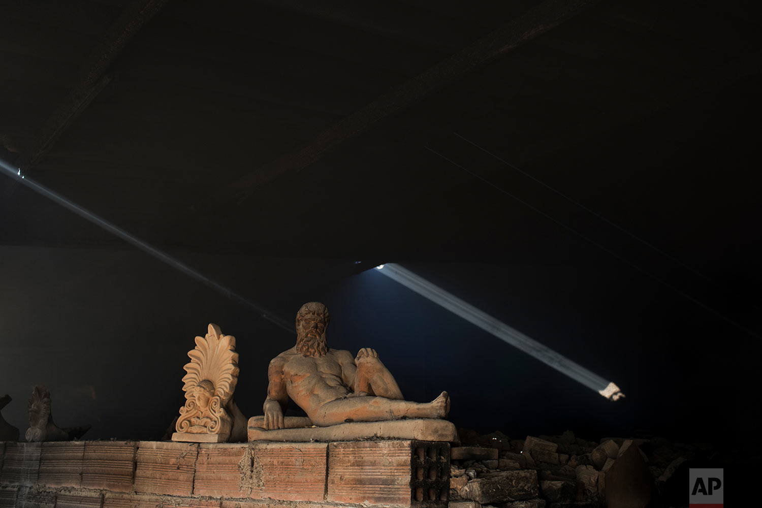  In this Friday, Nov. 20, 2017 photo, a sooty, dust-covered terracotta statue of Greek mythological hero Hercules, a son of Zeus, stands on top of a burning furnace next to an antefix in Haralambos Goumas' sculpture and ceramic workshop, in the Egale