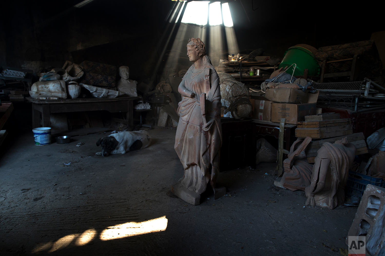  In this Friday, Nov. 20, 2017 photo, a dog lies next to a terracotta statue of Erato, one of the nine Muses of ancient Greek mythology, stands in Haralambos Goumas' ceramic workshop, in the Egaleo suburb of Athens. (AP Photo/Petros Giannakouris) 