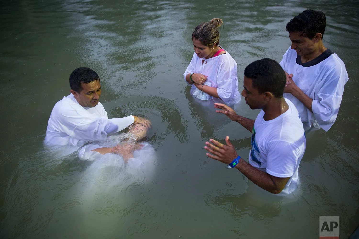 In this Tuesday, Jan. 31, 2017 photo, a Brazilian priest baptizes a Christian pilgrim in the Jordan River at Yardenit baptismal site in northern Israel. (AP Photo/Oded Balilty)