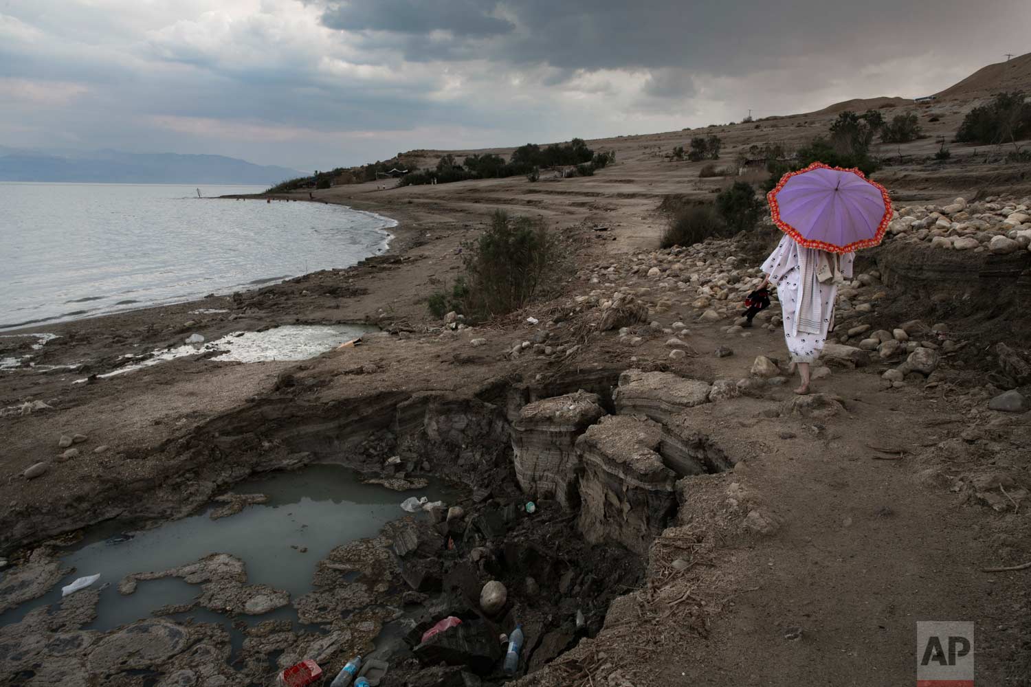  In this April 2, 2017 photo, a woman walks next to sinkholes along the Dead Sea shore near the Israeli Kibbutz of Ein Gedi. (AP Photo/Oded Balilty) 