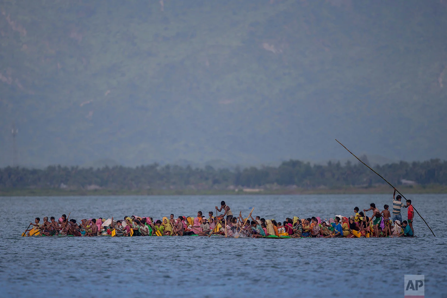 In this Nov. 12, 2017, photo, Rohingya Muslims travel on a raft made with plastic containers on which they crossing over the Naf river from Myanmar into Bangladesh, near Shah Porir Dwip, Bangladesh. Many of the refugees who have been flooding into Bangladesh to escape the Myanmar military say they're hopeful that a visit to the region by Pope Francis will help bring peace. Francis will be treading a difficult diplomatic line on his visit to Bangladesh and Myanmar, where he is due to arrive Monday afternoon. (AP Photo/A.M. Ahad)