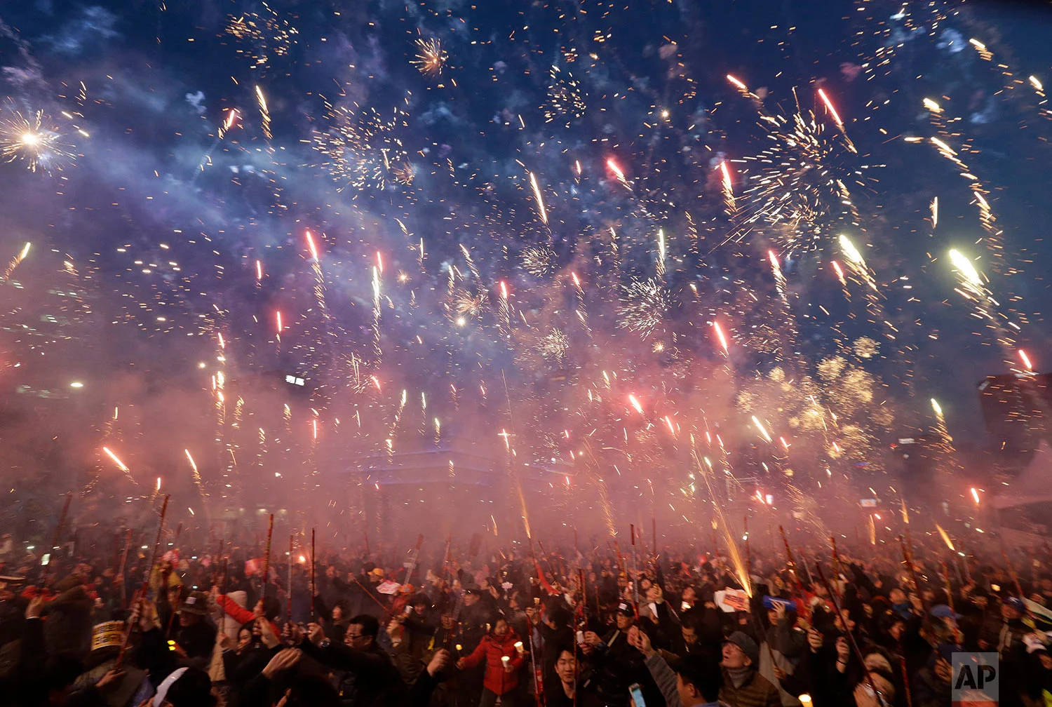 Protesters set off fireworks during a candle light vigil calling for impeached President Park Geun-hye's arrest in Seoul, South Korea, Saturday, March 11, 2017. South Korean police on Saturday braced for more violence between opponents and supporters of ousted President Park Geun-hye, who was stripped of her powers by the Constitutional Court over a corruption scandal that has plunged the country into a political turmoil. (AP Photo/Ahn Young-joon)