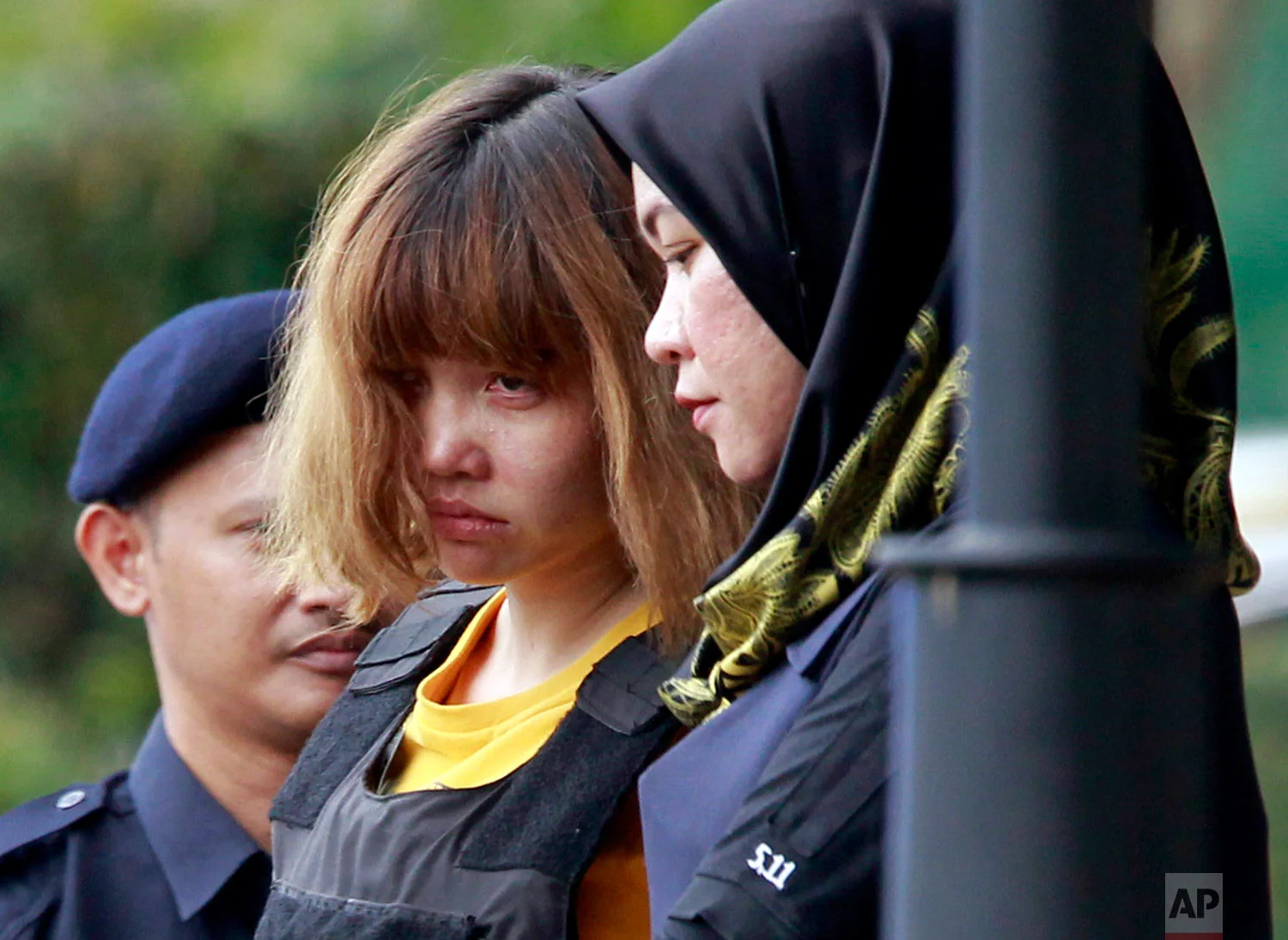 In this March 1, 2017, photo, Vietnamese Doan Thi Huong, center, a suspect in the ongoing investigation into the assassination of Kim Jong Nam, is escorted by police from Sepang court in Sepang, Malaysia. Appearing calm and solemn, two young women accused of smearing VX nerve agent on Kim Jong Nam, the estranged half brother of North Korea's leader, were charged with murder. (AP Photo/Daniel Chan)