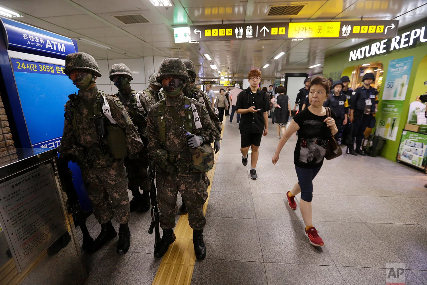Passengers walk past South Korean army soldiers during an anti-terror drill as part of Ulchi Freedom Guardian exercise, at a subway station in Seoul, South Korea, Tuesday, Aug. 22, 2017. As North Korea vowed "merciless retaliation" against U.S.-South Korean military drills it claims are an invasion rehearsal, senior U.S. military commanders on Tuesday dismissed calls to pause or downsize exercises they called crucial to countering a clear threat from Pyongyang. (AP Photo/Ahn Young-joon)
