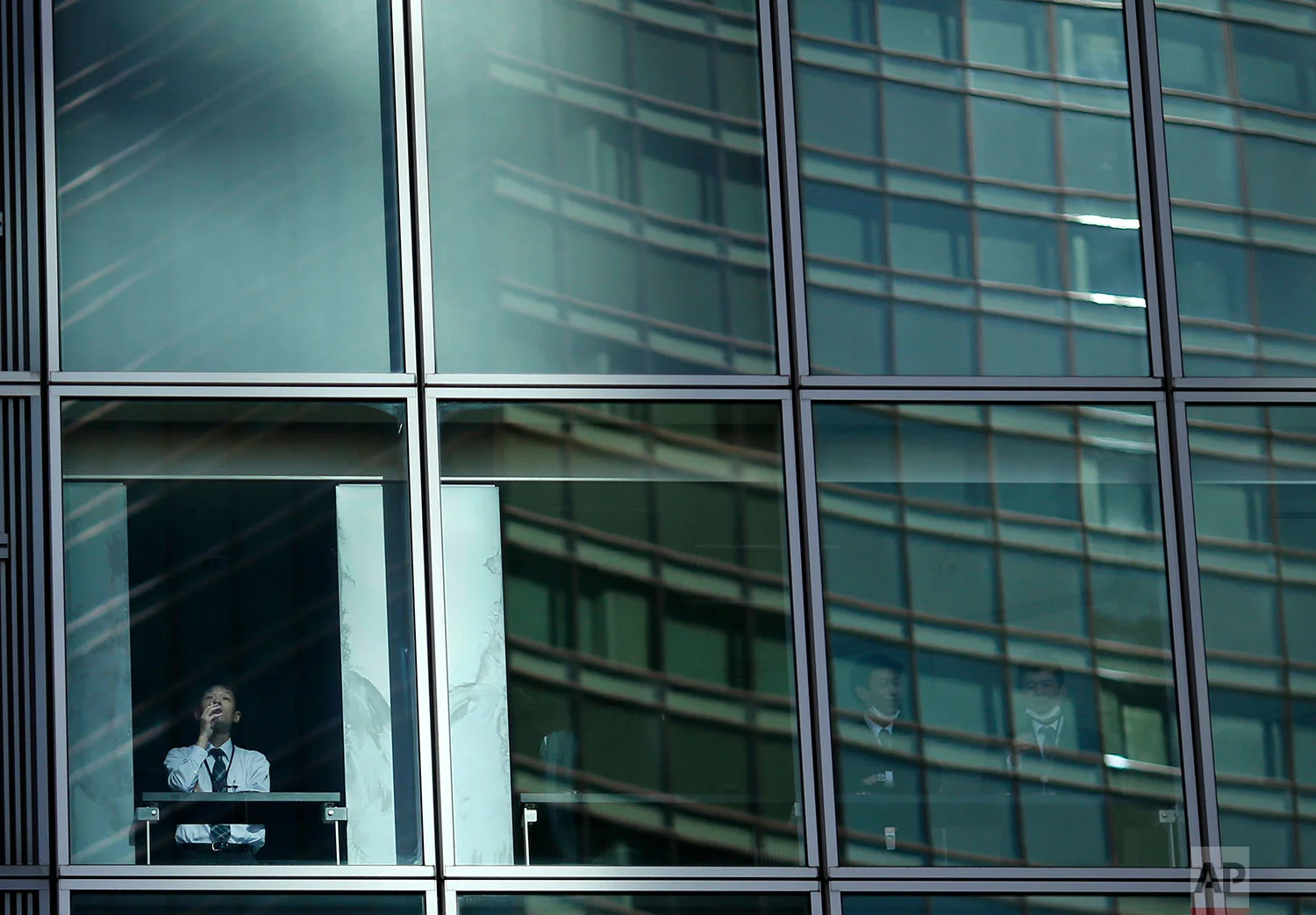 In this Wednesday, Jan. 11, 2017 photo, an employee smokes at the window of a high-rise building in a Tokyo's business area. (AP Photo/Shuji Kajiyama)