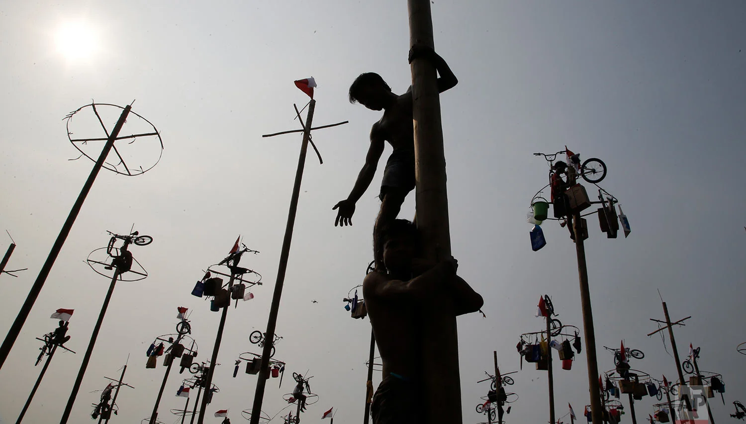 Participants assist each other in greased-pole climbing competition held as a part of independence day celebration at Ancol Beach in Jakarta, Indonesia, Thursday, Aug 17, 2017. Contestants race up to grab items ranging from buckets to bicycles hanging from the top of the poles as prize. Indonesia is celebrating its 72th anniversary of independence from the Netherlands. (AP Photo/Achmad Ibrahim)