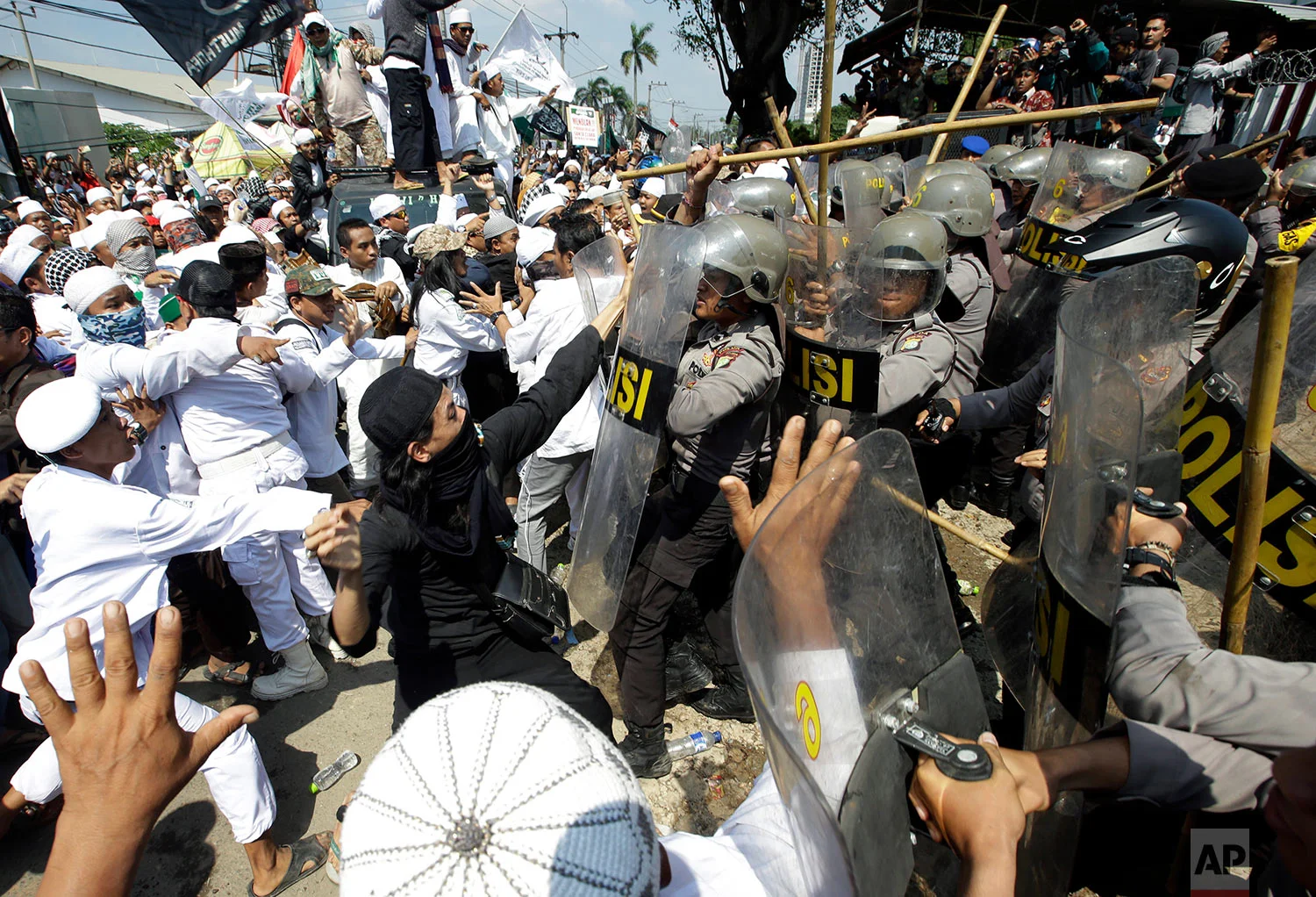 In this Friday, March 24, 2017 photo, police officers clash with Muslim hardliners during a protest against the construction of a Catholic church in Bekasi, Indonesia. Indonesian police fired tear gas to disperse the protesters as they tried to force their way into the Santa Clara church, which has been under construction since November. (AP Photo/Achmad Ibrahim)