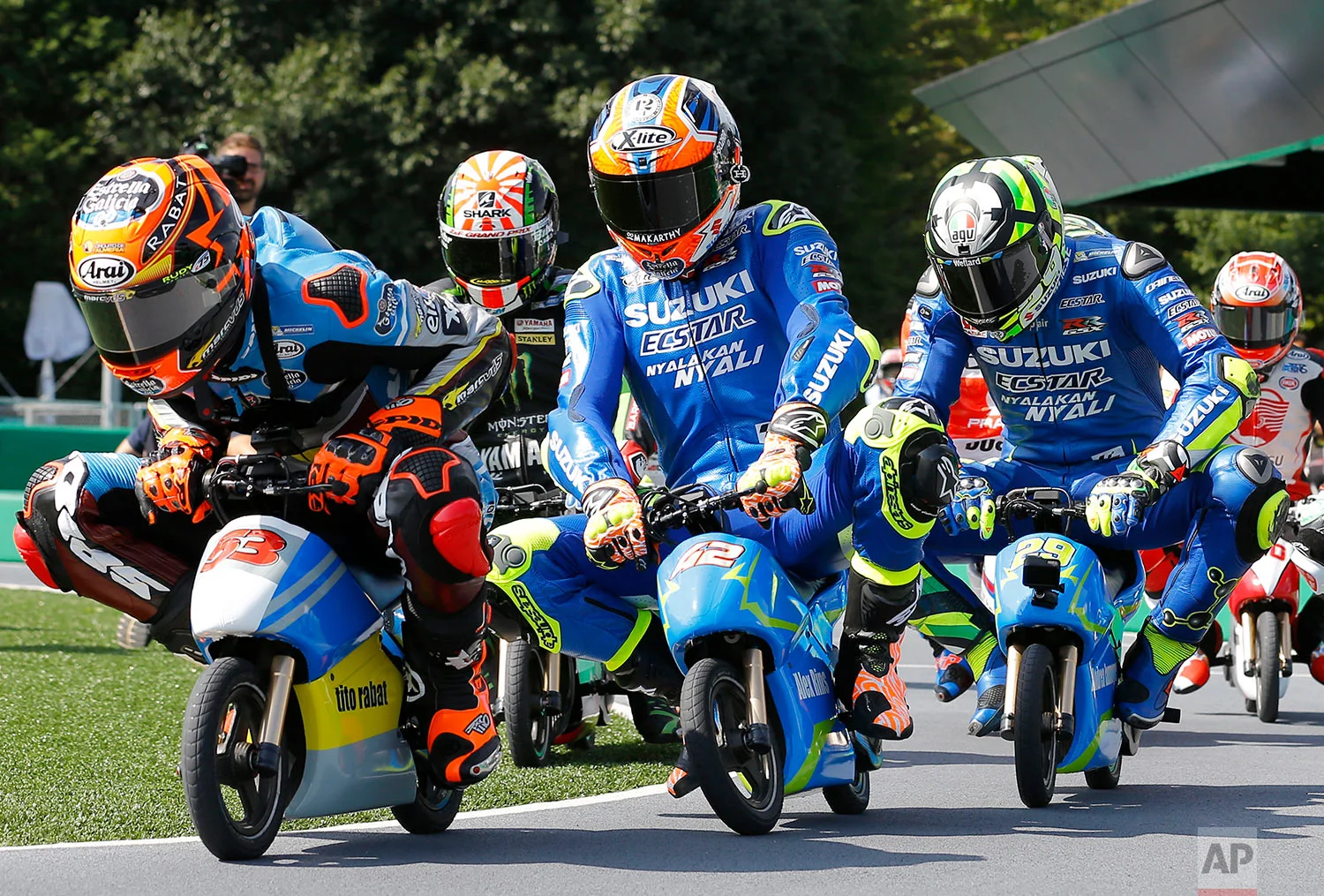 In this Tuesday, Oct. 10, 2017, photo, MotoGP rider Tito Rabat, left, of Spain steers his mini electric motorcycle as he leads the pack of riders during a fan event at the Twin Ring Motegi circuit ahead of the MotoGP Japanese Motorcycle Grand Prix in Motegi, north of Tokyo. (AP Photo/Shizuo Kambayashi)