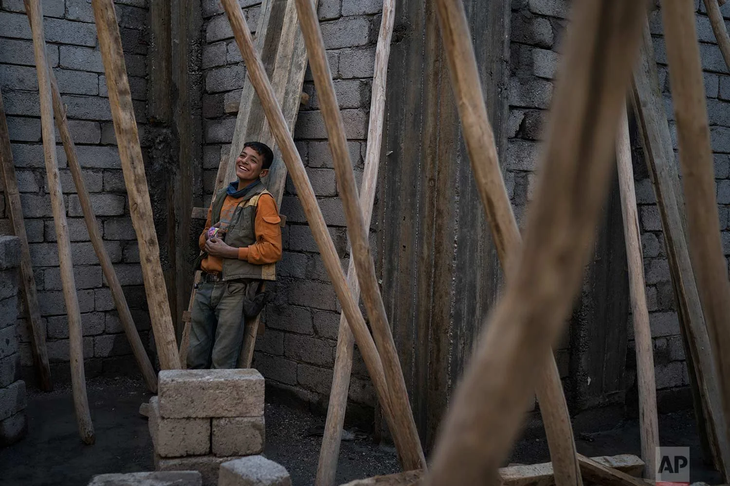 In this Nov. 14, 2017 photo, a young construction worker smiles during a break as he rebuilds a destroyed shop in the Old City of Mosul, Iraq. (AP Photo/Felipe Dana)