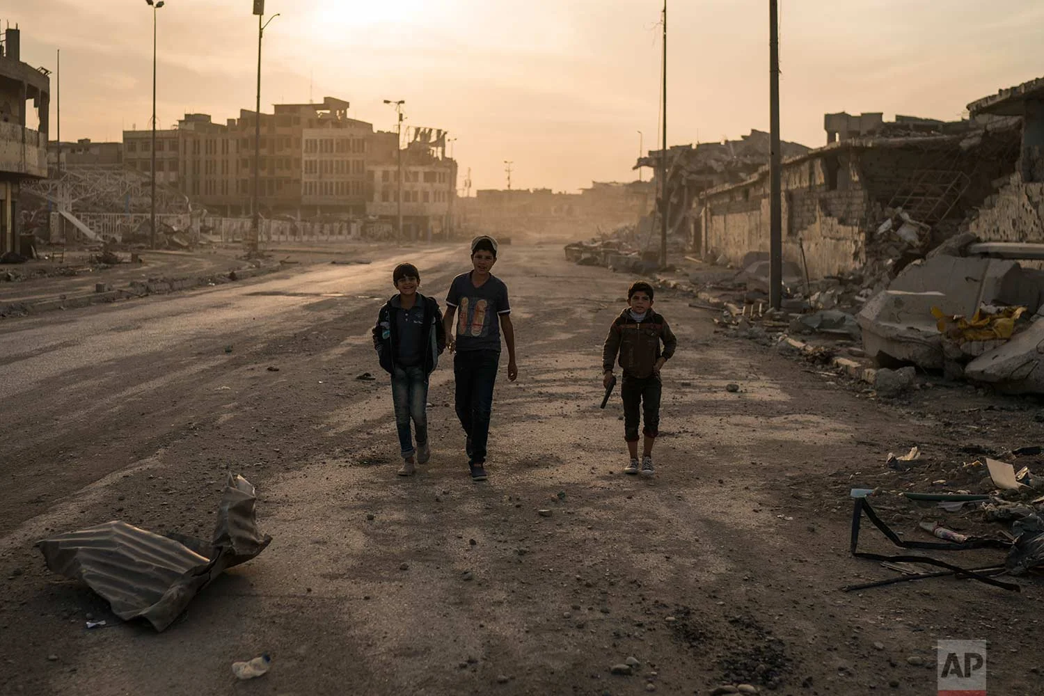 In this Nov. 15, 2017 photo, boys, one of them carrying a toy gun, walk on the empty streets of the Old City, in Mosul, Iraq. (AP Photo/Felipe Dana)