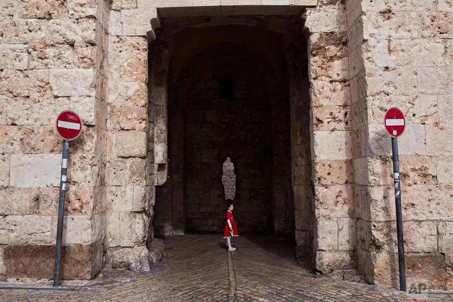 In this Tuesday, Dec. 19, 2017 photo, a young girl waits for her family to cross the Zion Gate in Jerusalem Old City. (AP Photo/Oded Balilty)