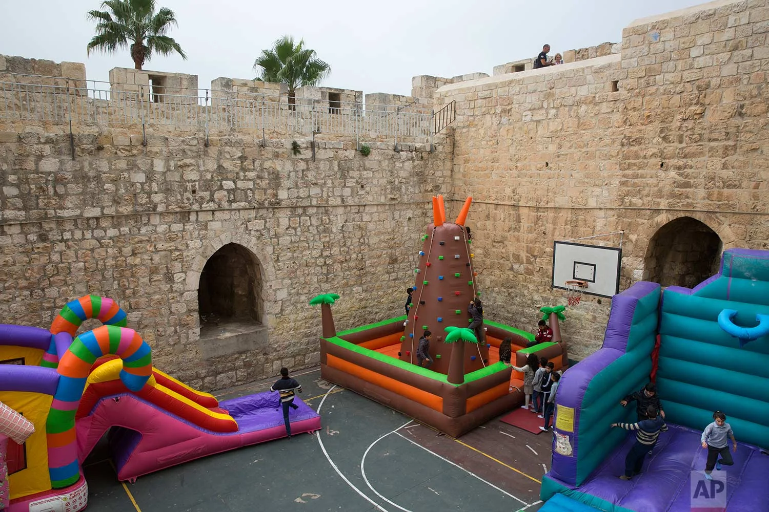 In this Thursday, Dec. 21, 2017 photo, Israeli Arab Christian school kids play on inflatables games in De La Salle school basketball yard surrounded by the Jerusalem's Old City walls next to the New Gate in Jerusalem Old City. (AP Photo/Oded Balilty)