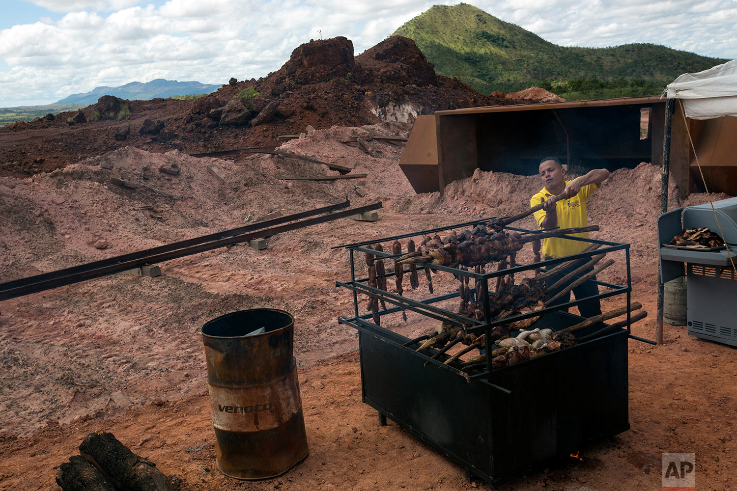  In this Nov. 2, 2017 photo, a Ferrominera Orinoco worker cooks sausages, pork and chicken to celebrate the completion of repairs on a set of damaged railroad tracks, in Ciudad Piar, Bolivar state, Venezuela. Some of the twisted rails and derailed tr