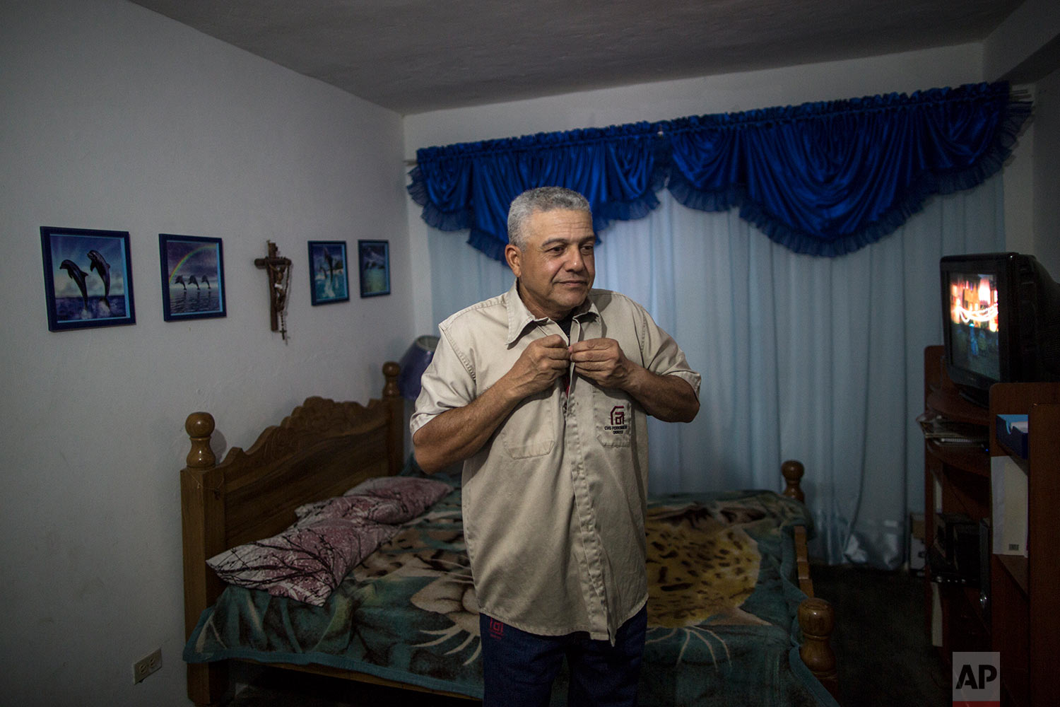  In this Nov. 5, 2017 photo, Tony Franco, who has worked for Ferrominera Orinoco for more than 28 years, puts on his uniform before leaving for the night shift, in Ciudad Guyana, Bolivar state, Venezuela. Franco had to sell his car and now walks seve