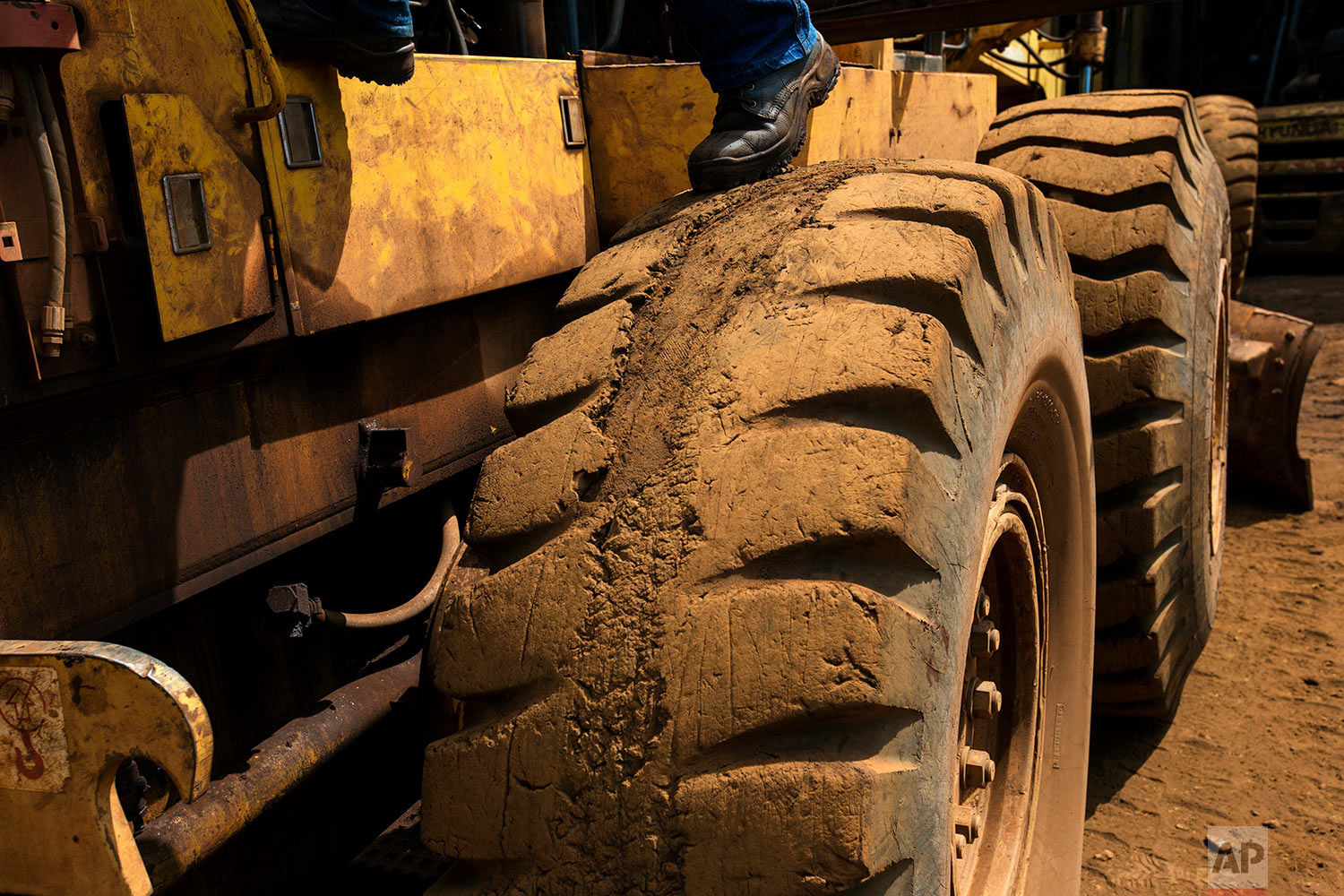  In this Nov. 4, 2017 photo, a worker repairs a truck at workshop at Ferrominera Orinoco, in Ciudad Piar, Bolivar state, Venezuela. The massive truc runs on a tire so badly worn that strips of rubber tread are missing. (AP Photo/Rodrigo Abd) 