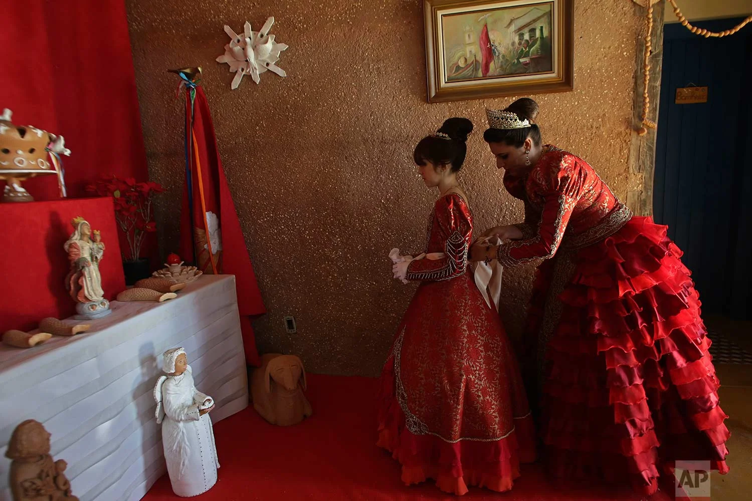 In this Nov. 12, 2017 photo published Friday, Dec. 1, Luana Borges helps her daughter Luana Silva dress for the Azorean Culture Festival, in Enseada de Brito, Brazil. (AP Photo/Eraldo Peres)
