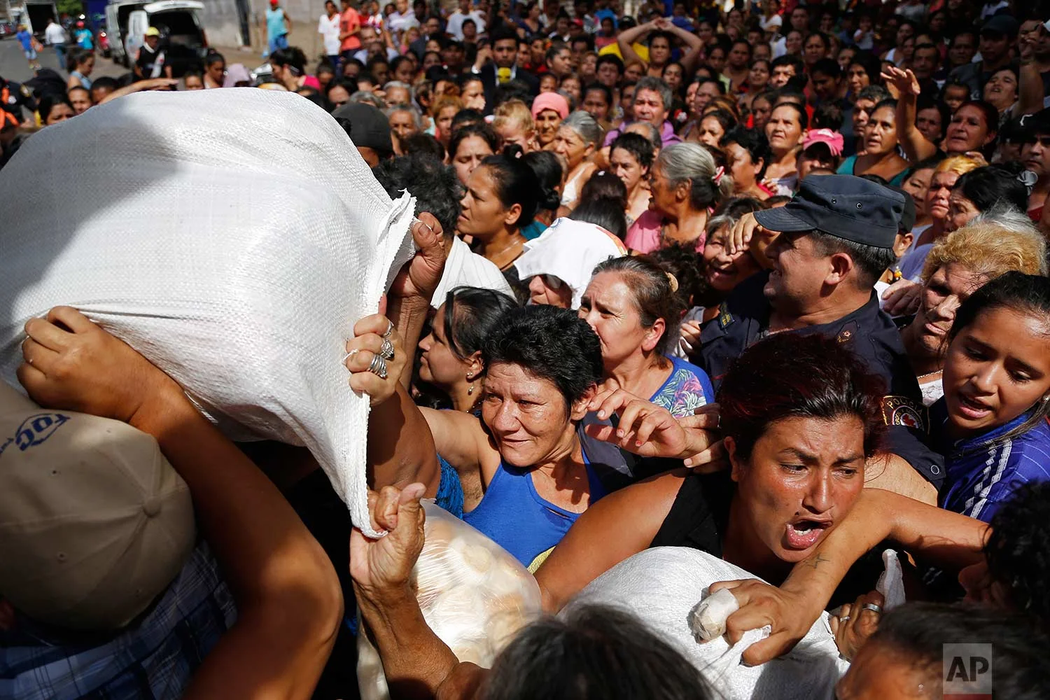 Residents reach out for free food from the relatives of two Mennonites kidnapped by the rebels of the Paraguay's People's Army (EPP) in the Pelopincho neighborhood of Asuncion, Paraguay, Tuesday, Dec. 19, 2017. (AP Photo/Jorge Saenz)