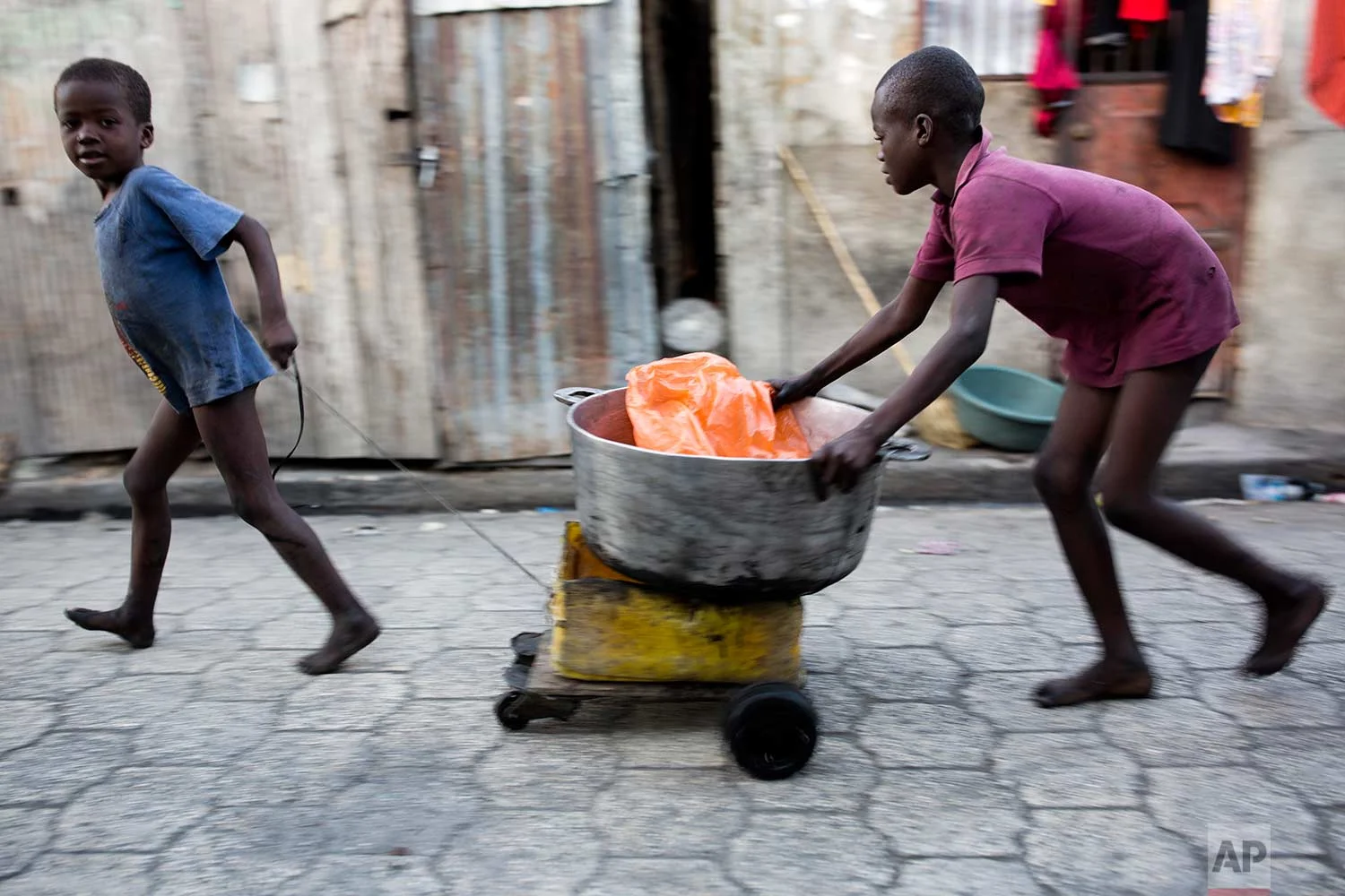 In this Dec. 27, 2017 photo, children transport a cooking bowl for their mother in the Cite Soleil slum of Port-au-Prince, Haiti. Cite Soleil is an extremely impoverished and densely populated slum located in the Port-au-Prince metropolitan area in Haiti. ( AP Photo/Dieu Nalio Chery)