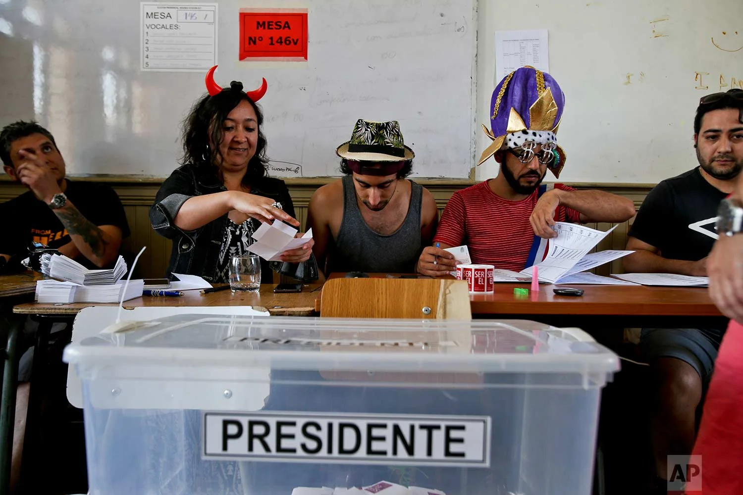Electoral workers sport costumes during the presidential runoff election in Santiago, Chile, Sunday, Dec. 17, 2017. Chileans will decide Sunday whether to swing the world's top copper-producing country to the right or maintain its center-left path in a fiercely contested election. (AP Photo/Esteban Felix)