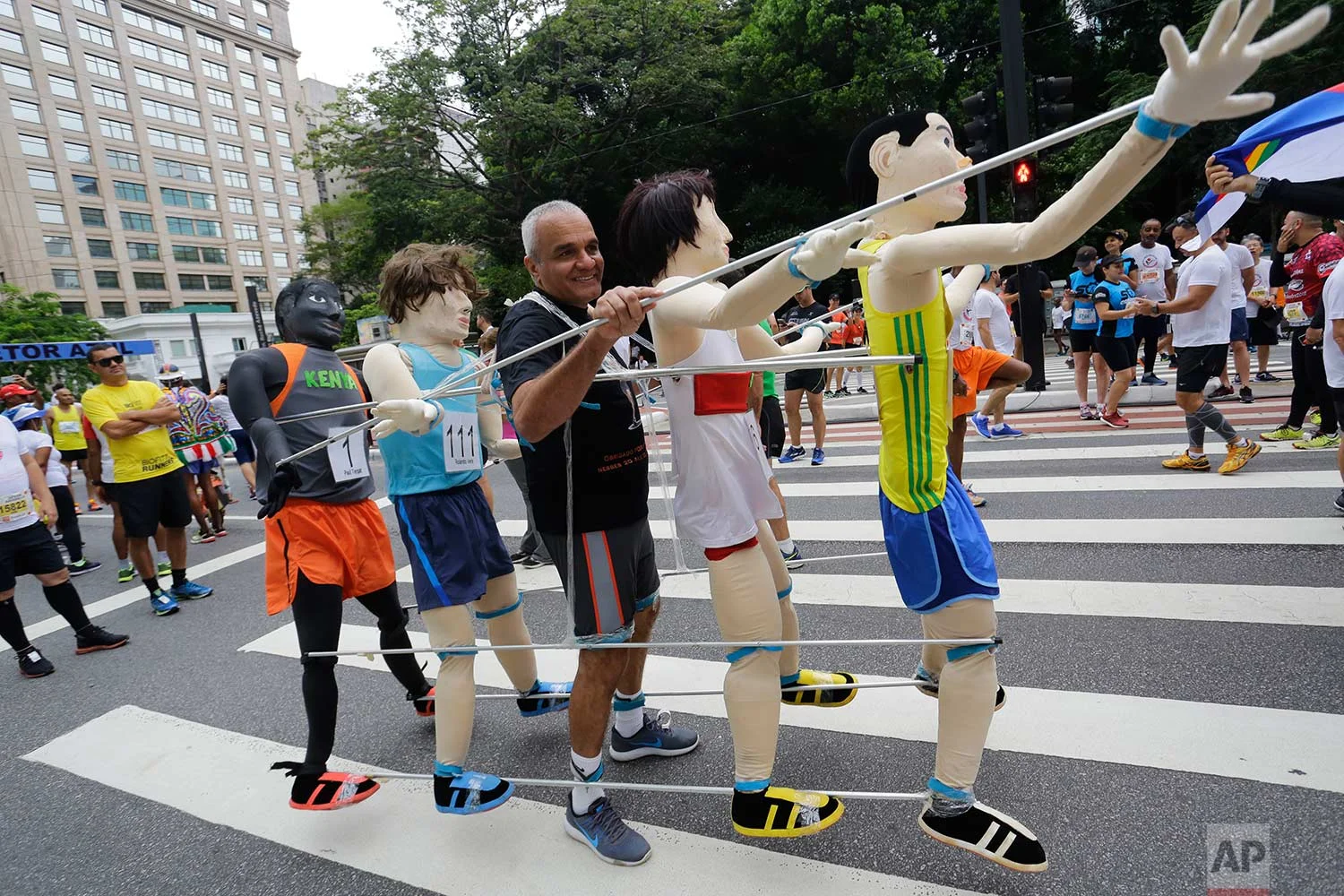 A runner stands with life-size puppets attached to him, prior to the start of the Sao Silvestre race in Sao Paulo, Brazil, early Sunday, Dec. 31, 2017. The 15-kilometer race is held annually on New Year's Eve. (AP Photo/Nelson Antoine)