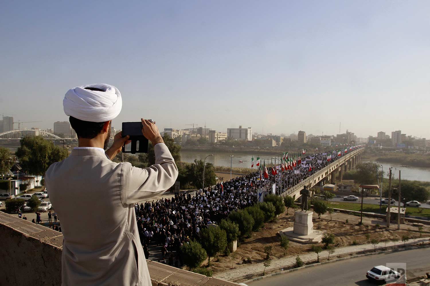  In this photo provided by the Iranian Students' News Agency, a clergyman takes a picture of a pro-government demonstration in the southwestern city of Ahvaz, Iran, Wednesday, Jan. 3, 2018. Tens of thousands of Iranians took part in pro-government de