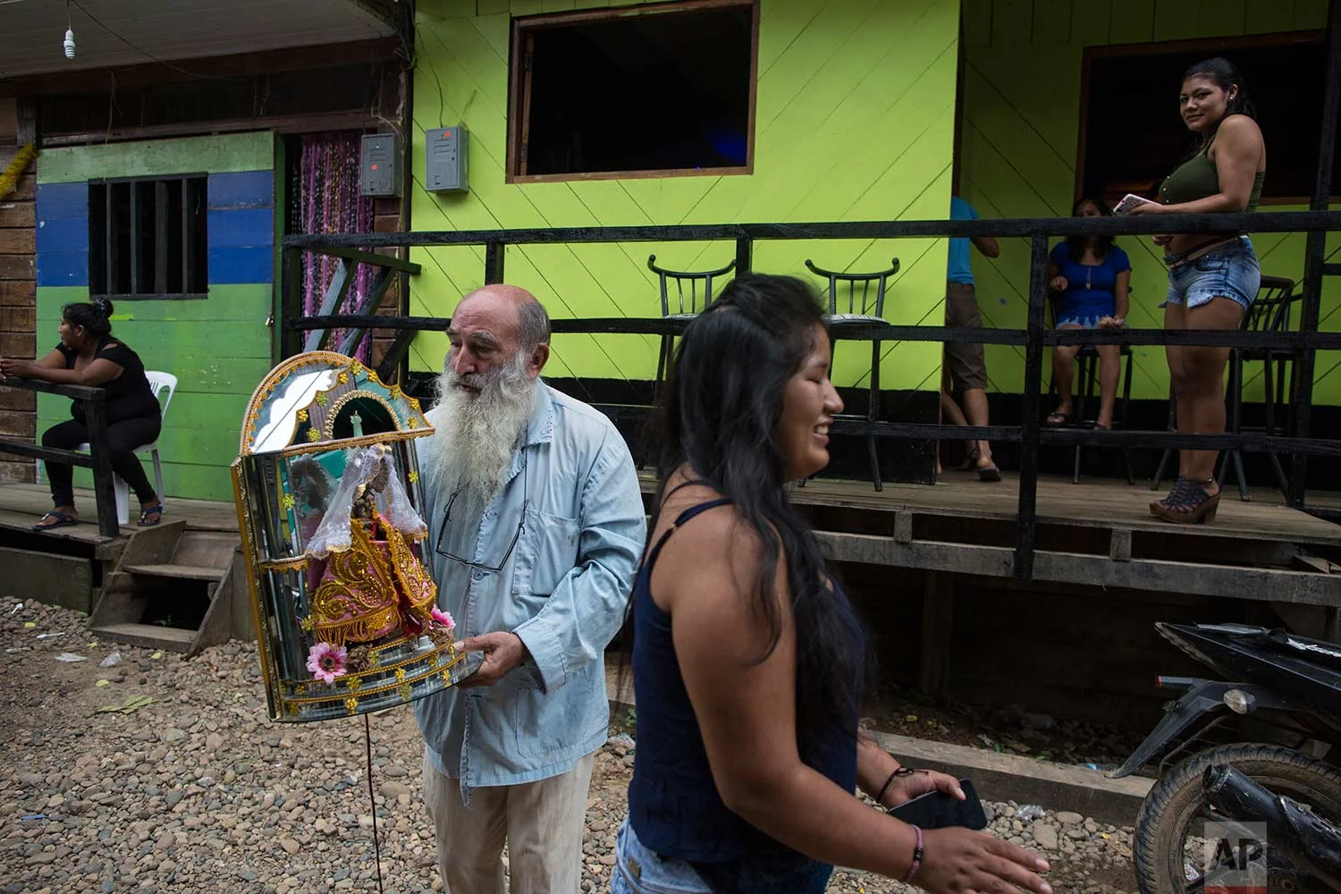 In this Jan. 10, 2018 photo, Father Pablo Zabala, better known as Padre Pablo, walks to the Barrio Chino bar to return a statue of Our Lady of Forgetfulness, Triumph and Mercy, adopted by the local sex workers as their patron saint, in Boca Colorado, part of Peru’s Madre de Dios region in the Amazon. (AP Photo/Rodrigo Abd) | See these photos on AP Images