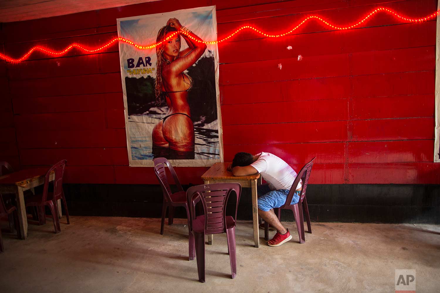In this Jan. 10, 2018 photo, a client sits passed out at the Nectar del Olvido bar, in Boca Colorado, part of Peru’s Madre de Dios region in the Amazon. (AP Photo/Rodrigo Abd) | See these photos on AP Images
