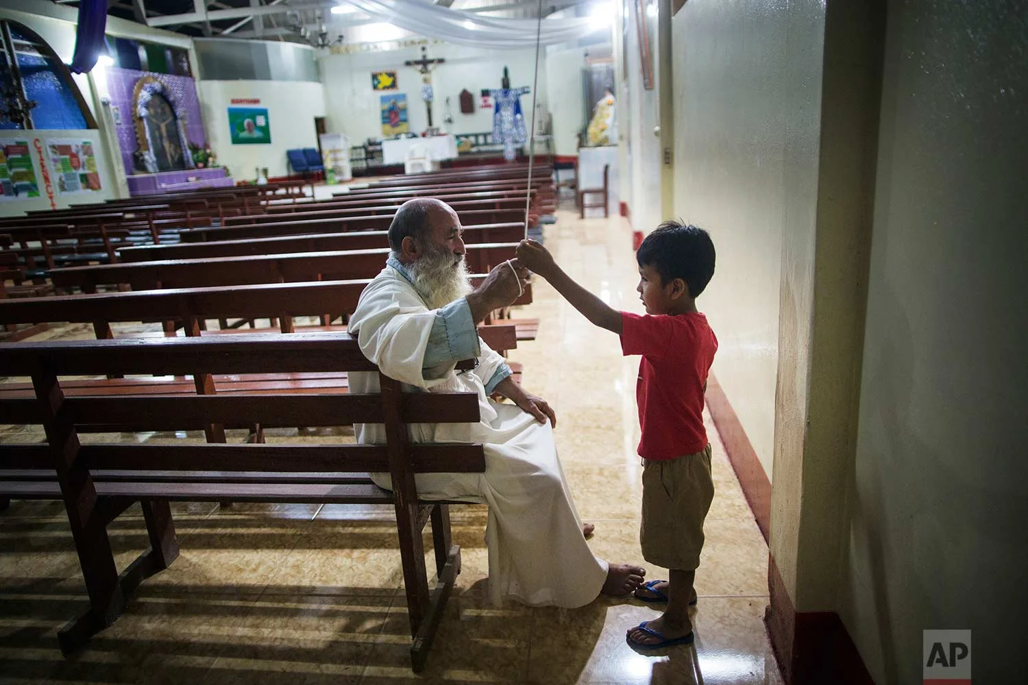 In this Jan. 13, 2018 photo, Father Pablo Zabala, better known as Padre Pablo, explains to five-year-old Valentino Cahuata how to properly ring the church bell to call the faithful to Mass, in Boca Colorado, part of Peru’s Madre de Dios region in the Amazon. (AP Photo/Rodrigo Abd) | See these photos on AP Images
