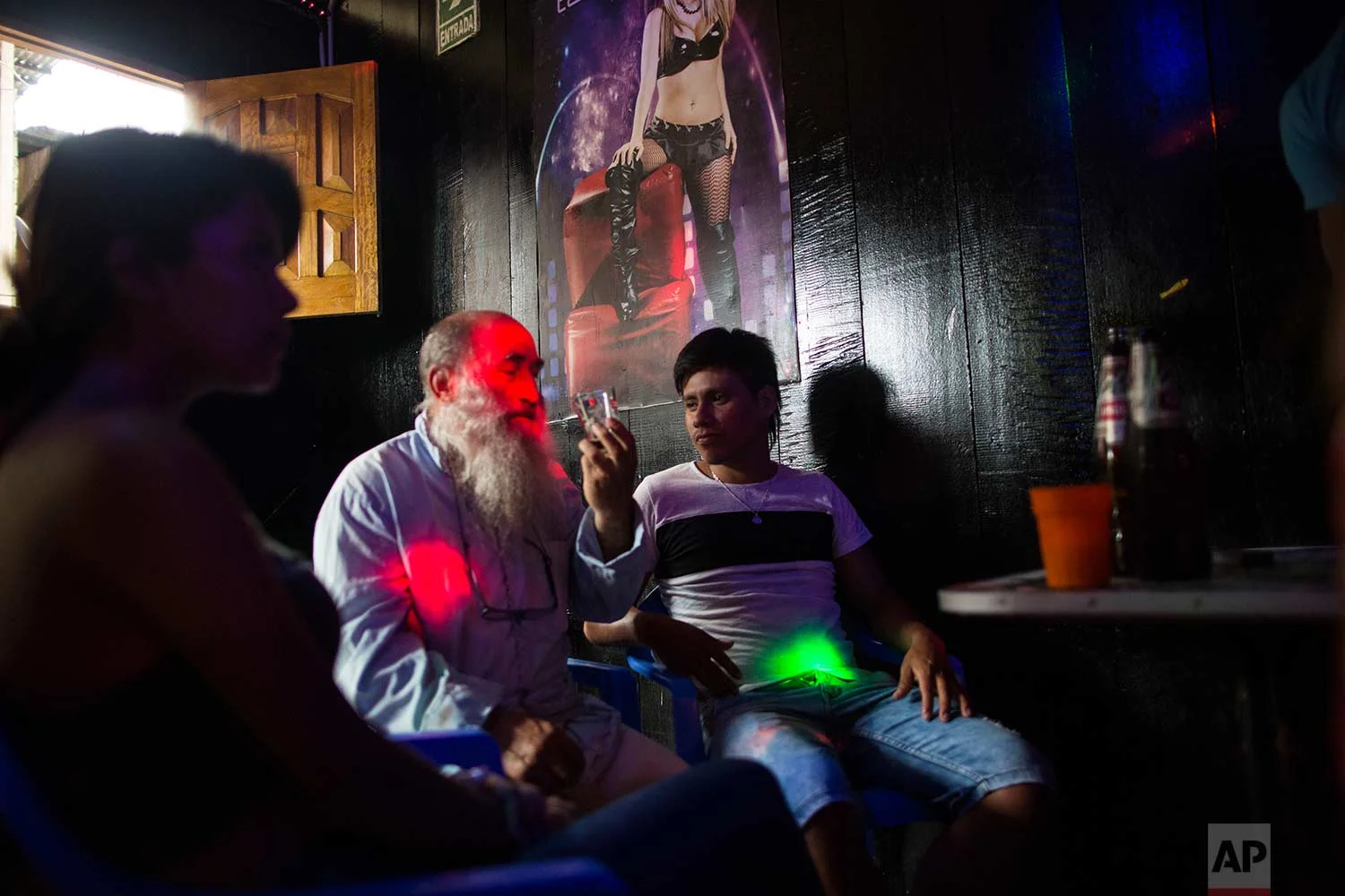 In this Jan. 10, 2018 photo, Father Pablo Zabala, better known as Padre Pablo, drinks a beer at the Nectar del Olvido bar, invited by men accompanied by sex workers in Boca Colorado, part of Peru’s Madre de Dios region in the Amazon. (AP Photo/Rodrigo Abd) | See these photos on AP Images