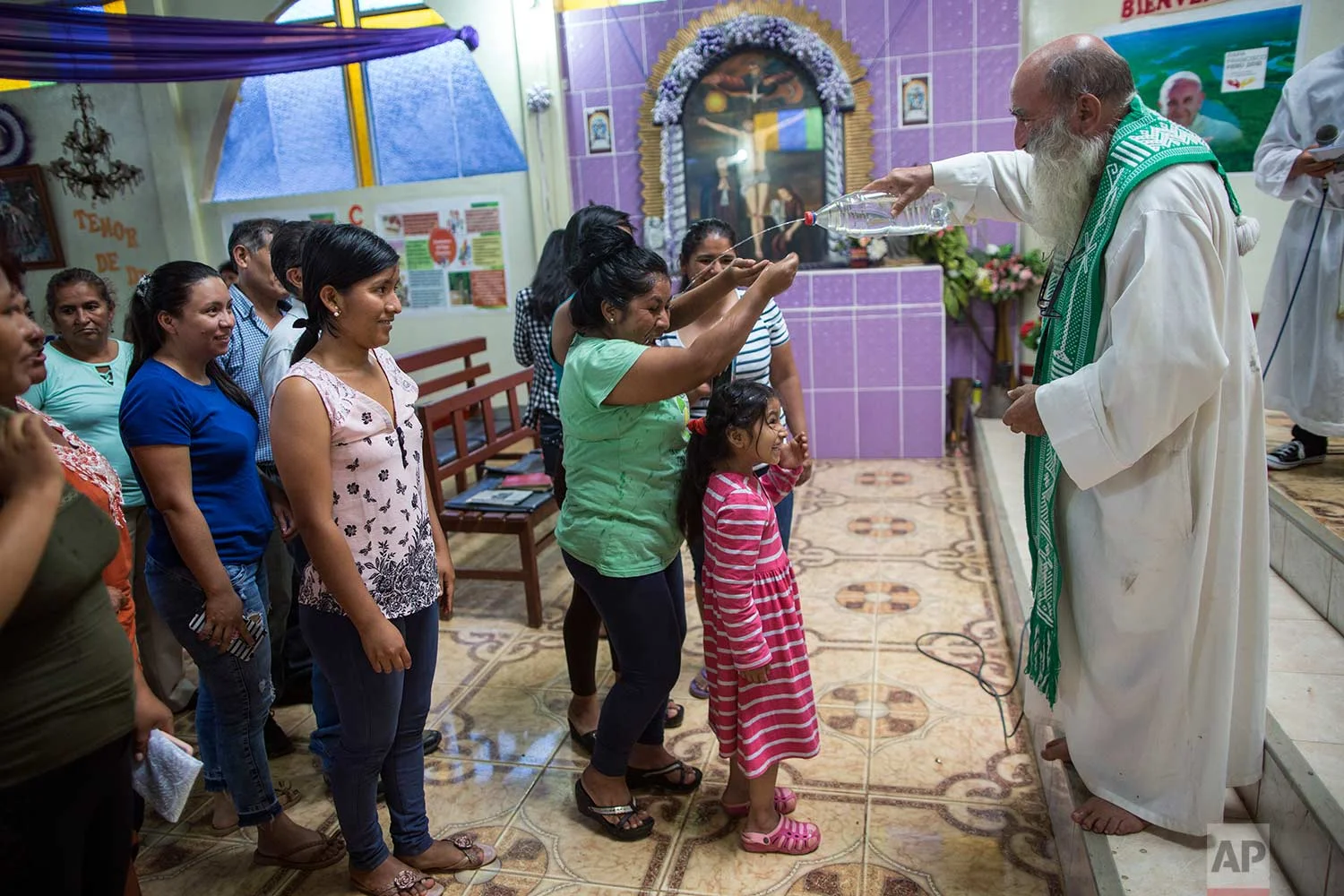 In this Jan. 14, 2018 photo, Father Pablo Zabala, better known as Padre Pablo, squirts holy water from a recycled water bottle during his last Mass as the parish priest in Boca Colorado, part of Peru’s Madre de Dios region in the Amazon. (AP Photo/Rodrigo Abd) | See these photos on AP Images